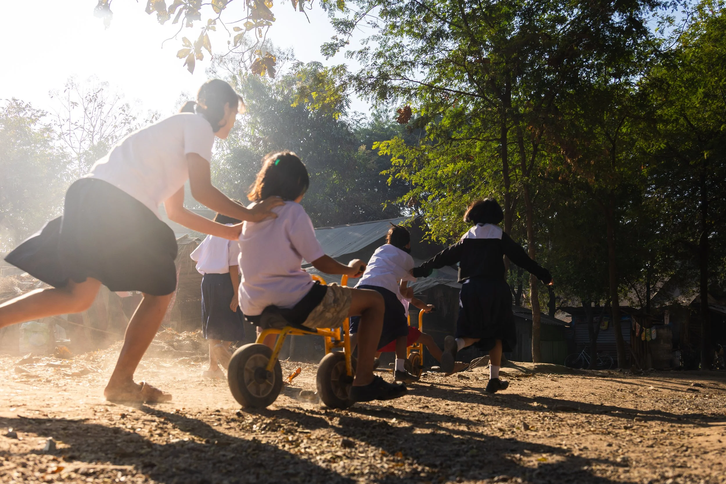 four female teachers standing in front of a bamboo school building