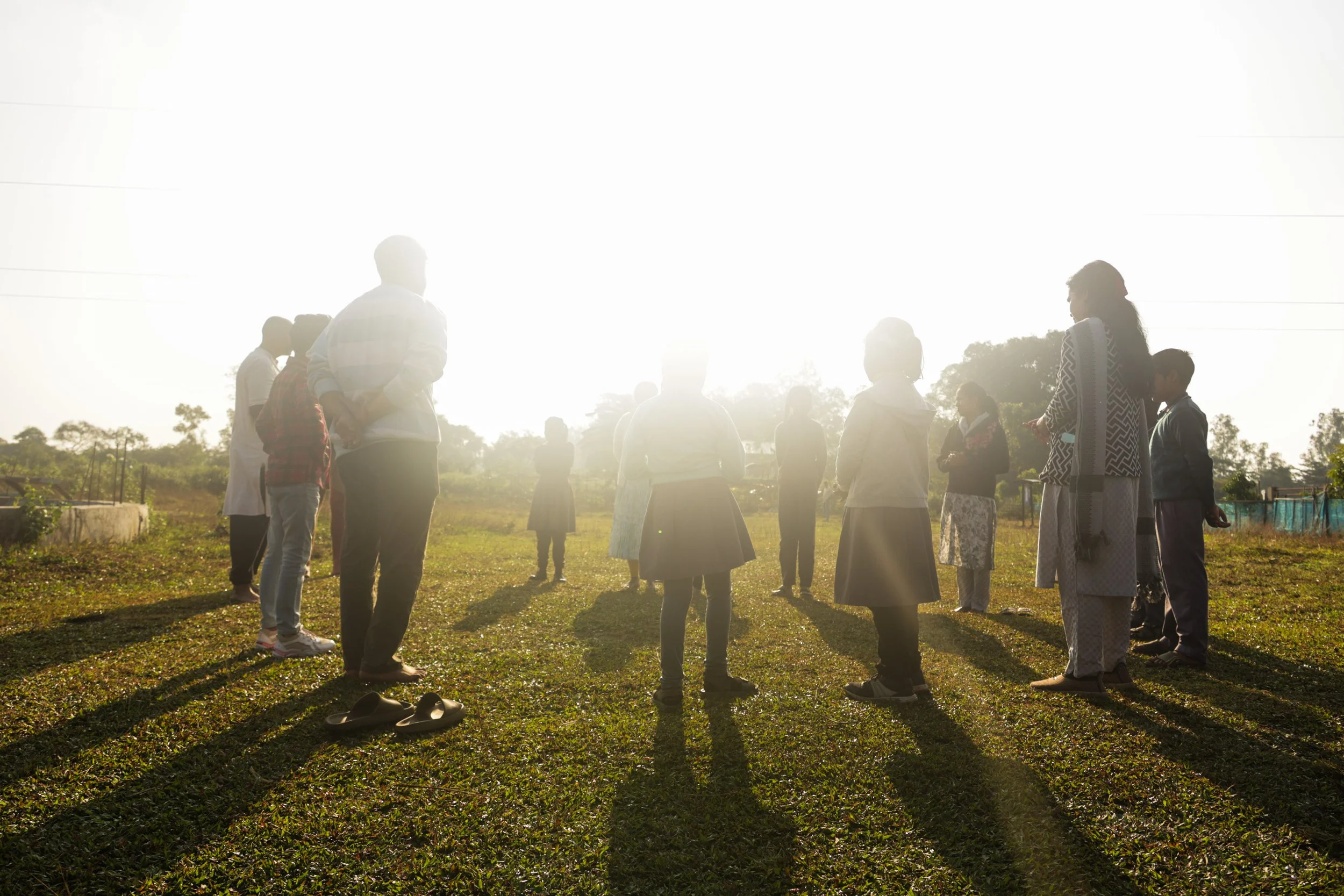 children standing in a circle outside in the sun