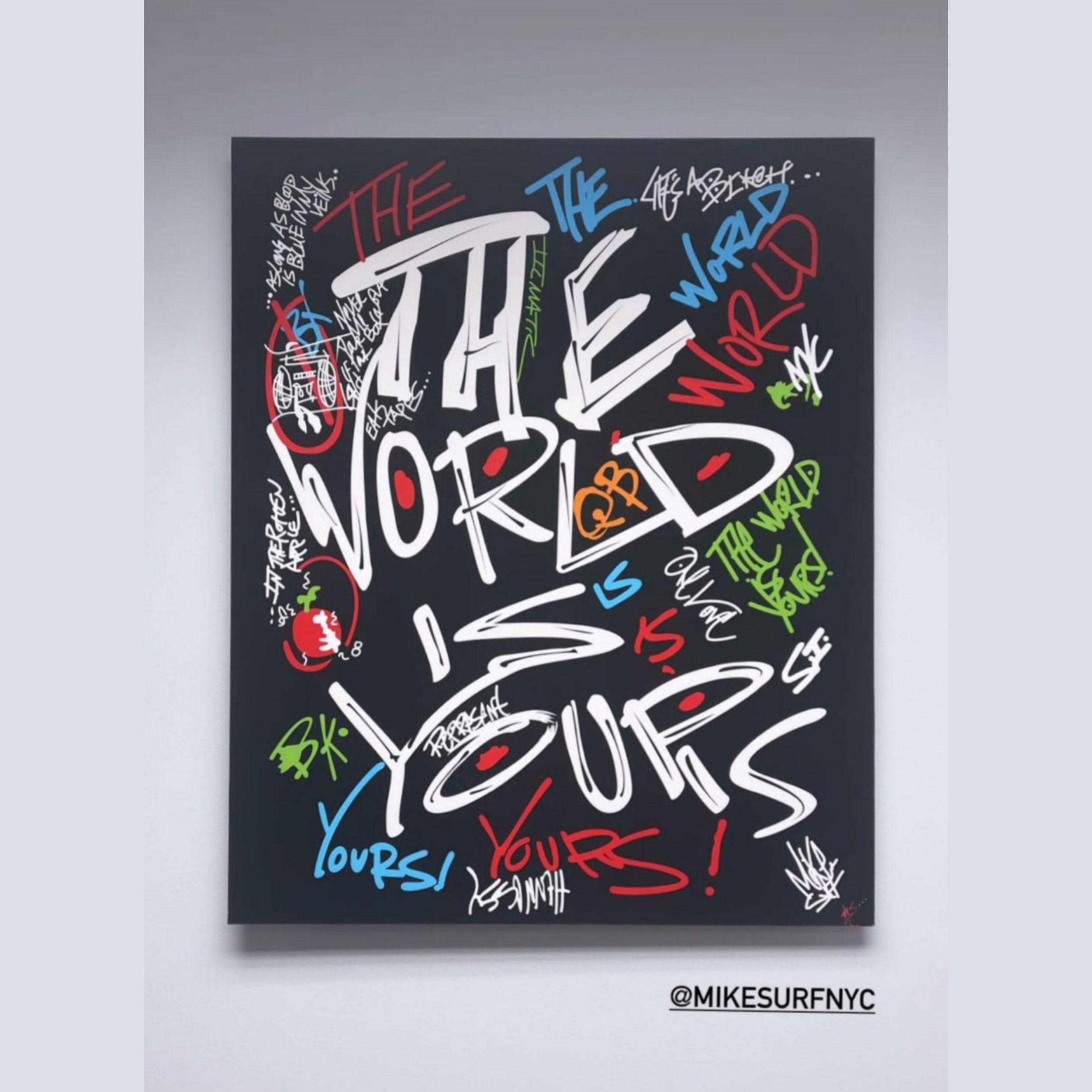 Graffiti art on a black canvas with bold text "The World is Yours" and various colorful tags, symbols, and signatures. Artist handle @mikesurfnyc visible.