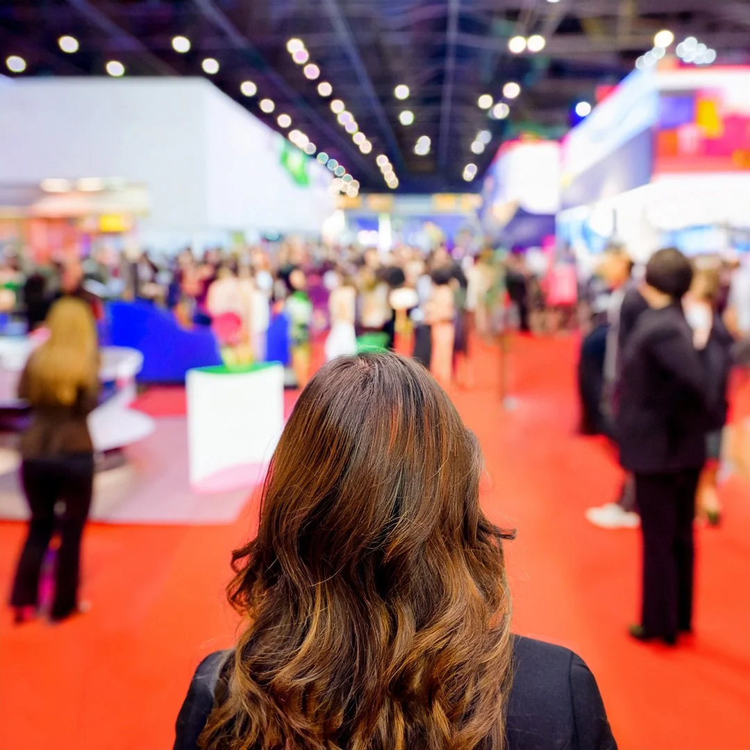 Woman looking over business event floor filled with people and exhibits