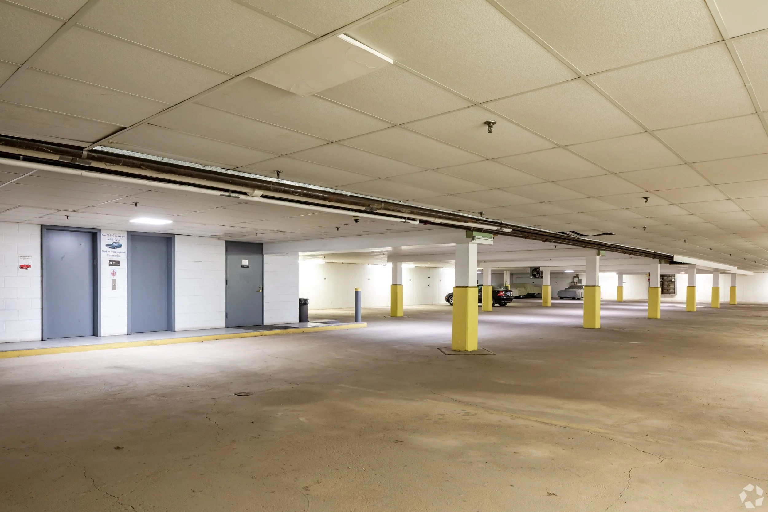 Indoor parking garage with yellow pillars, two cars, and a lighted ceiling