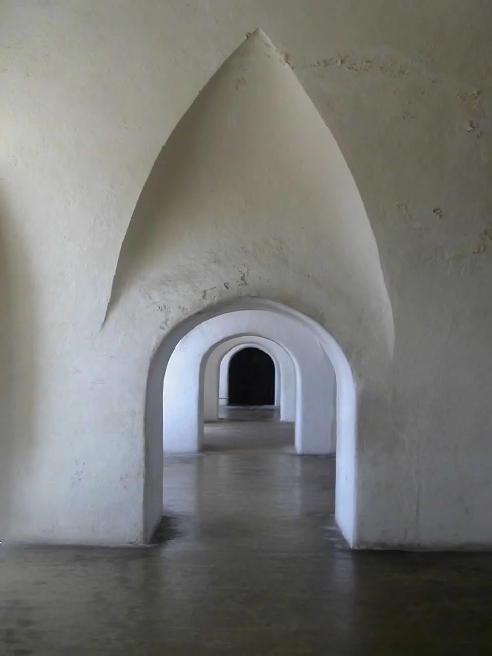 Multiple archways in a white, textured wall, creating a tunnel effect.