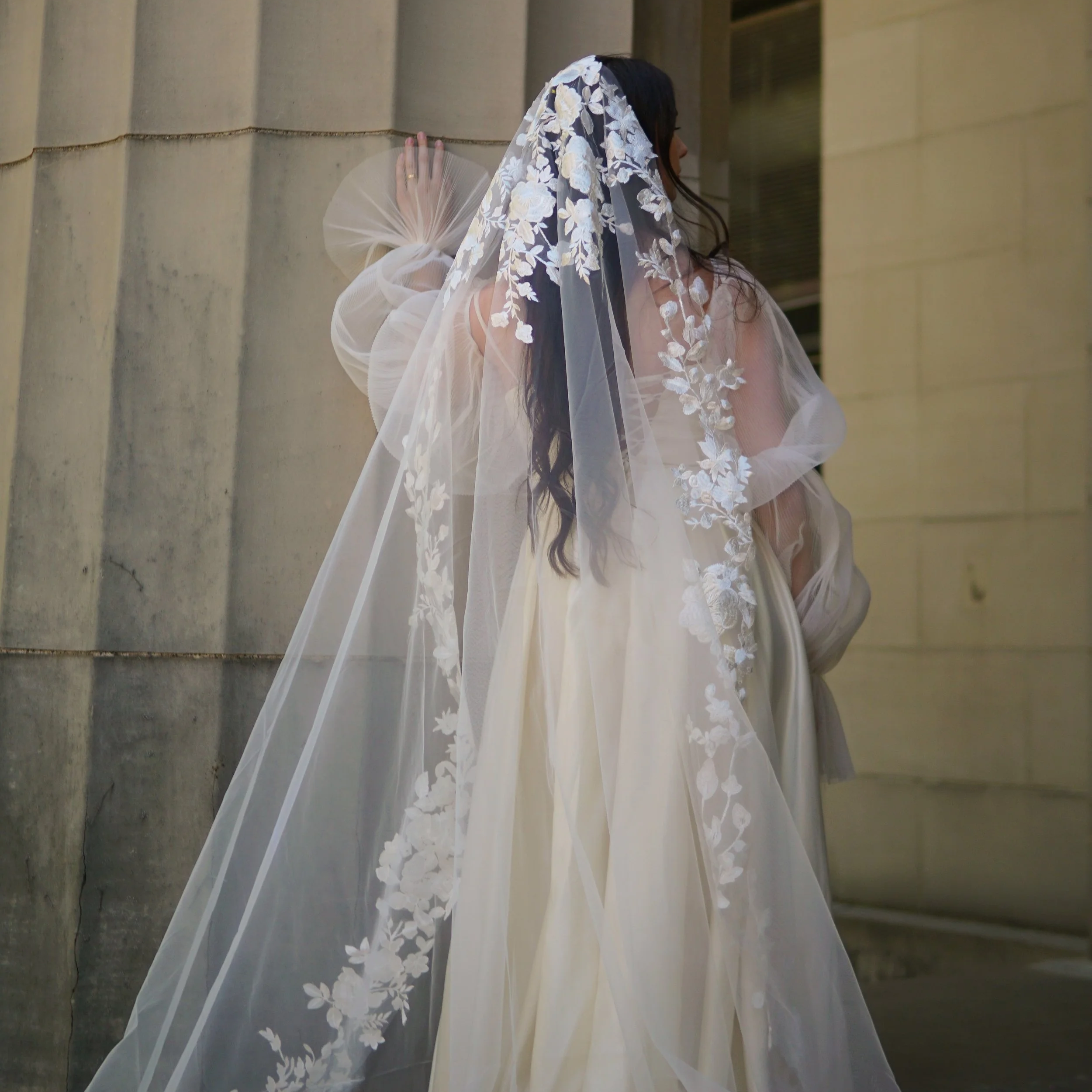 Close-up detail of the Lucia Mantilla veil showcasing intricate lace at the head area, featuring a delicate mix of small and large floral motifs and branching botanical patterns.