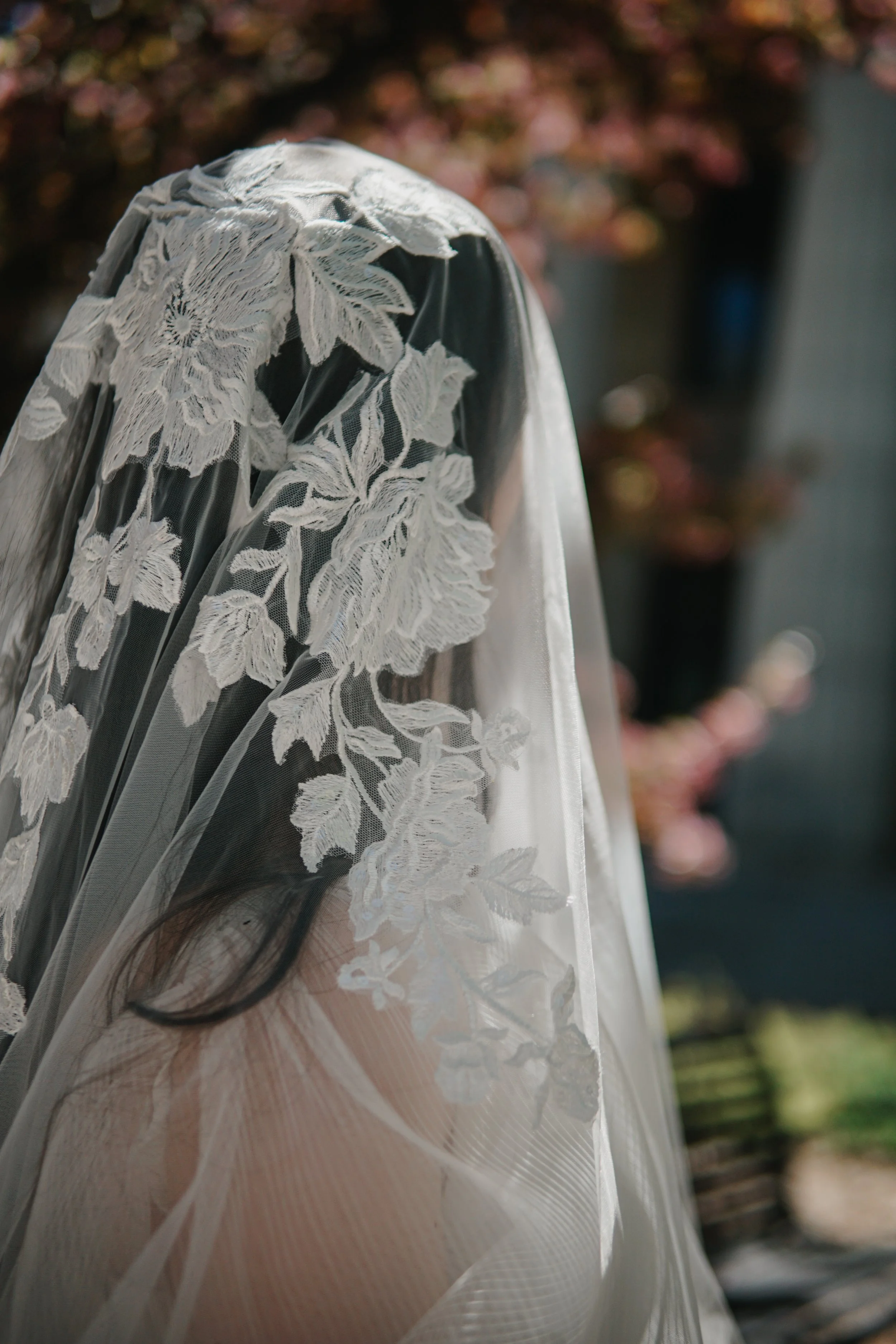 Close picture of the floral lace veil near the head area with flowers and branches