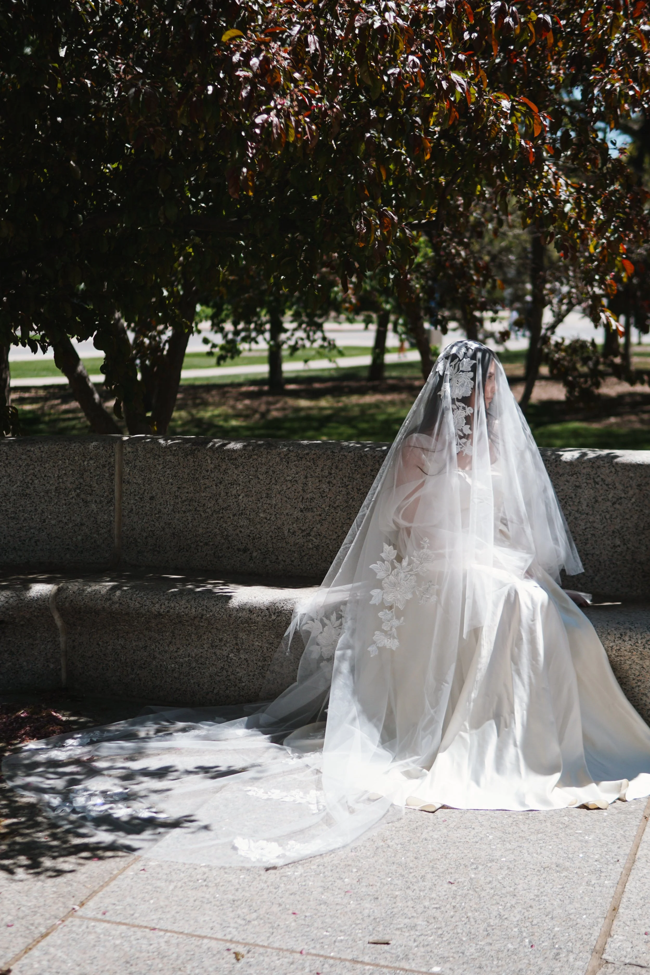 Bride wearing a blusher floral lace veil in cathedral length. The lace is covering face partially from the side.