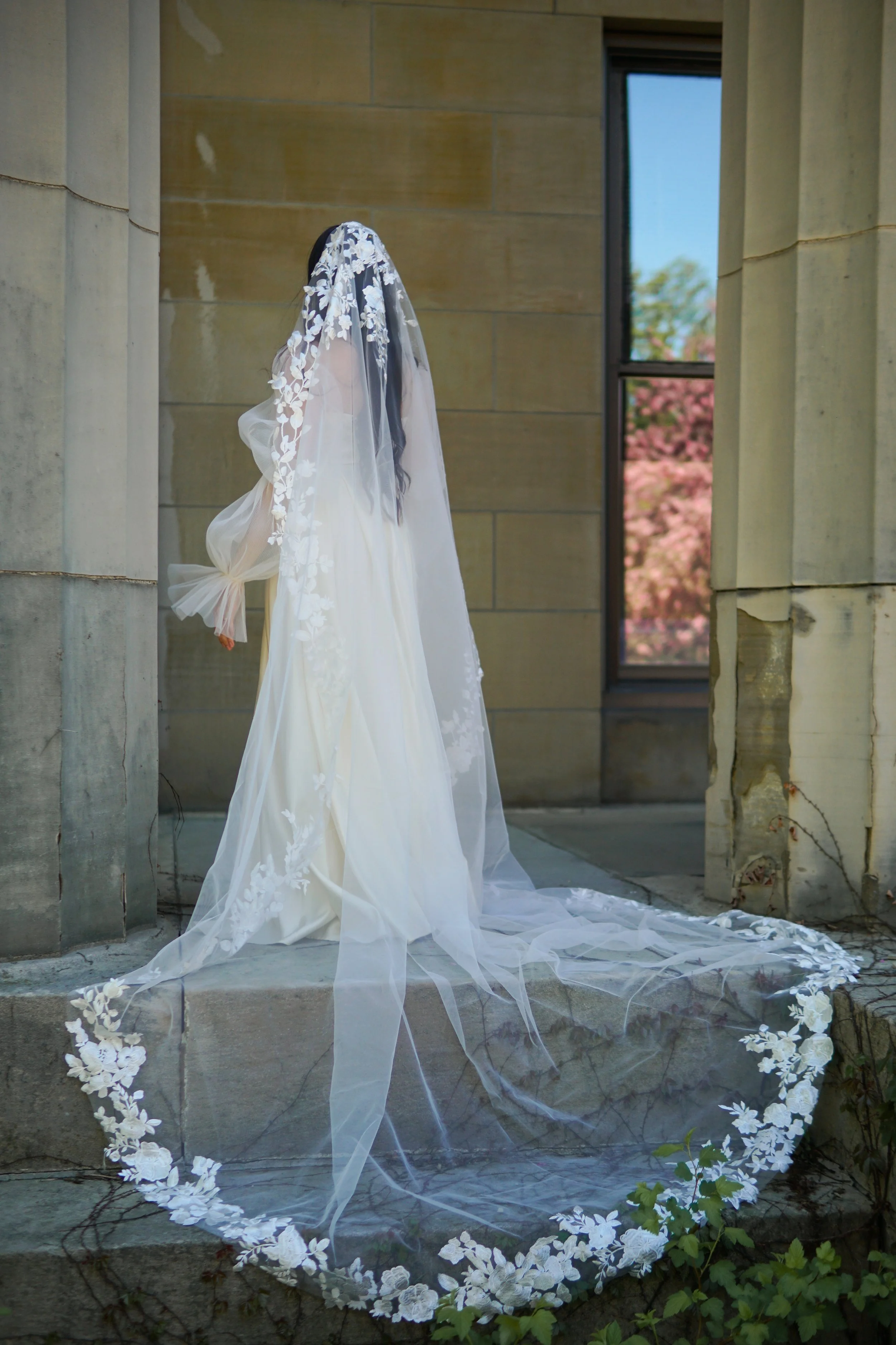 Bride wearing a romantic cathedral-length mantilla wedding veil adorned with intricate floral lace appliqués.