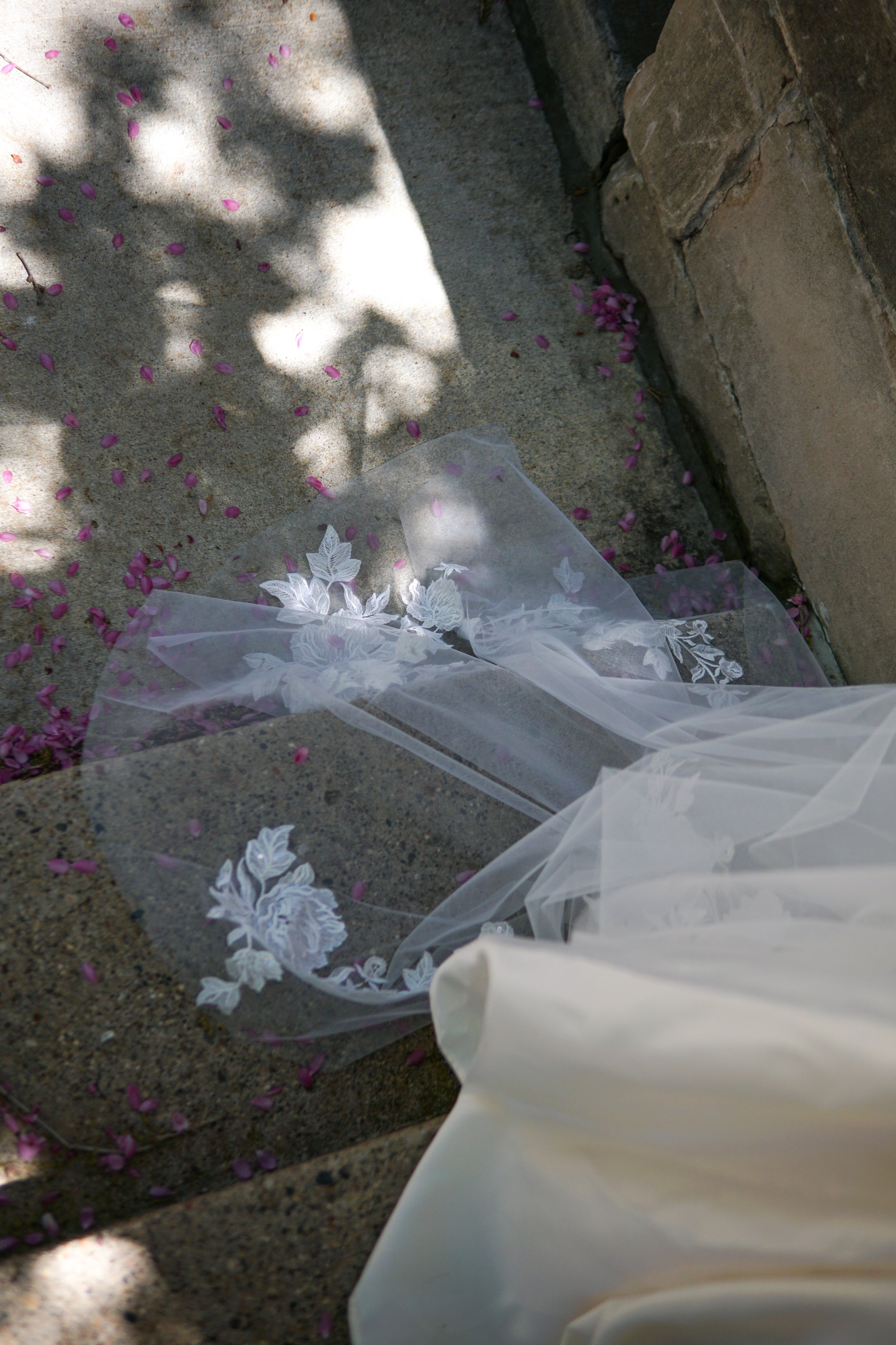 The photo shows part of the veil laid on a stone floor, highlighting the large floral lace appliqués in detail.