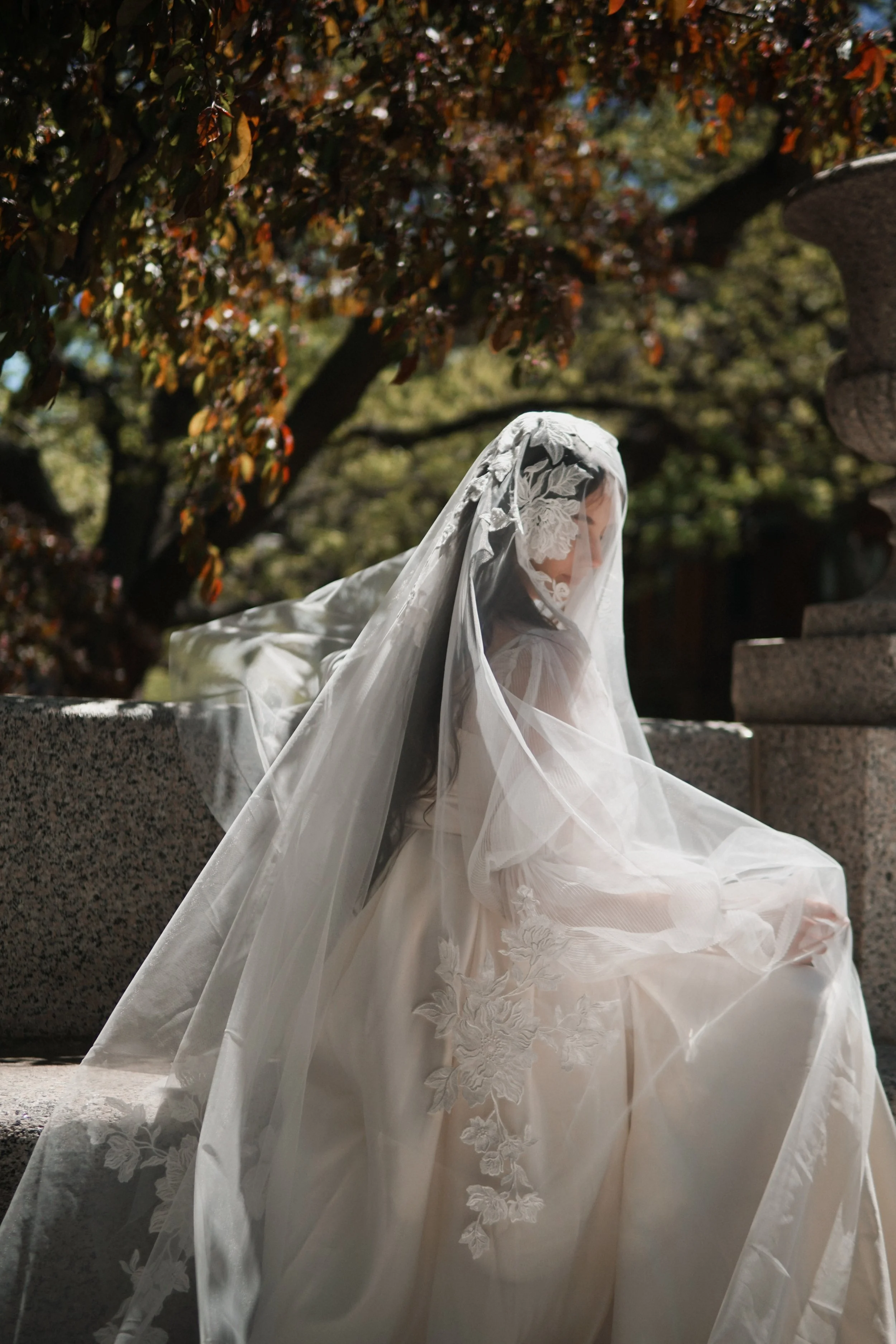 Close picture of a Bride wearing a floral lace veil with blusher. The large flower on the veil is covering face partially