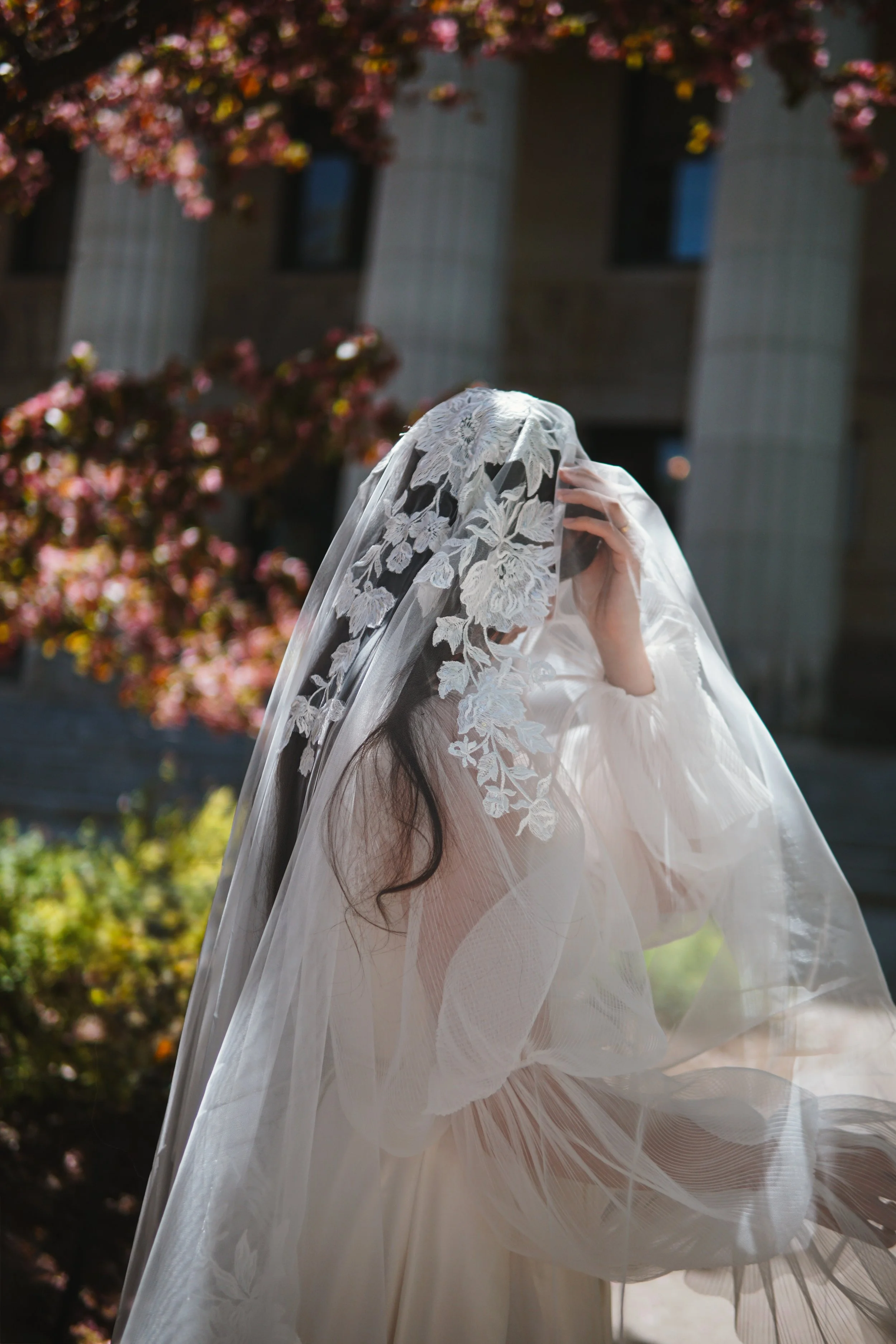 Close picture of the bride wit floral lace veil on the entire head area with mix of large and small flowers and branches