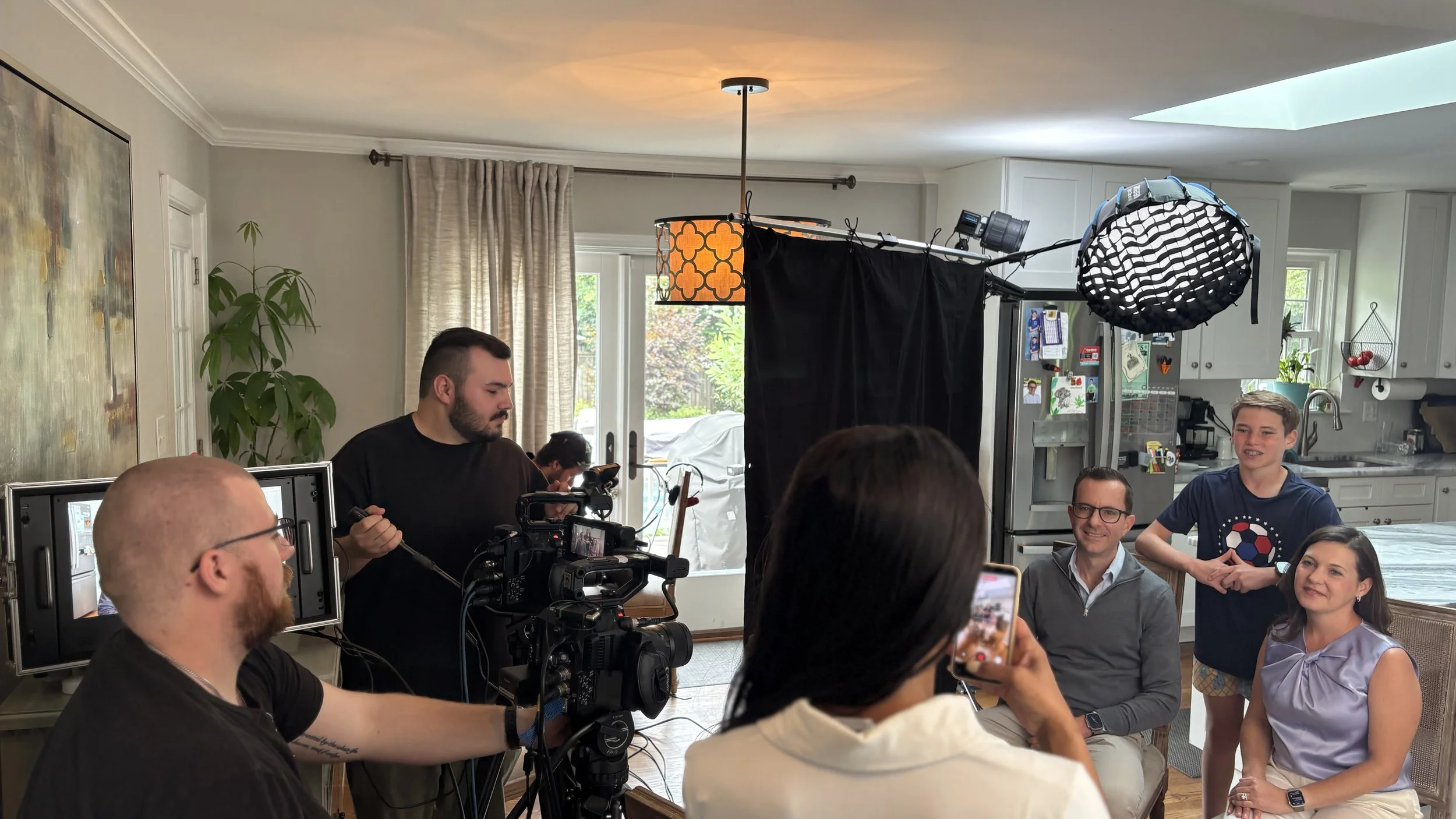 Corporate interview: Gaffing and Grip Work
People participating in a photo or video shoot in a home kitchen and dining area, with professional camera equipment visible.