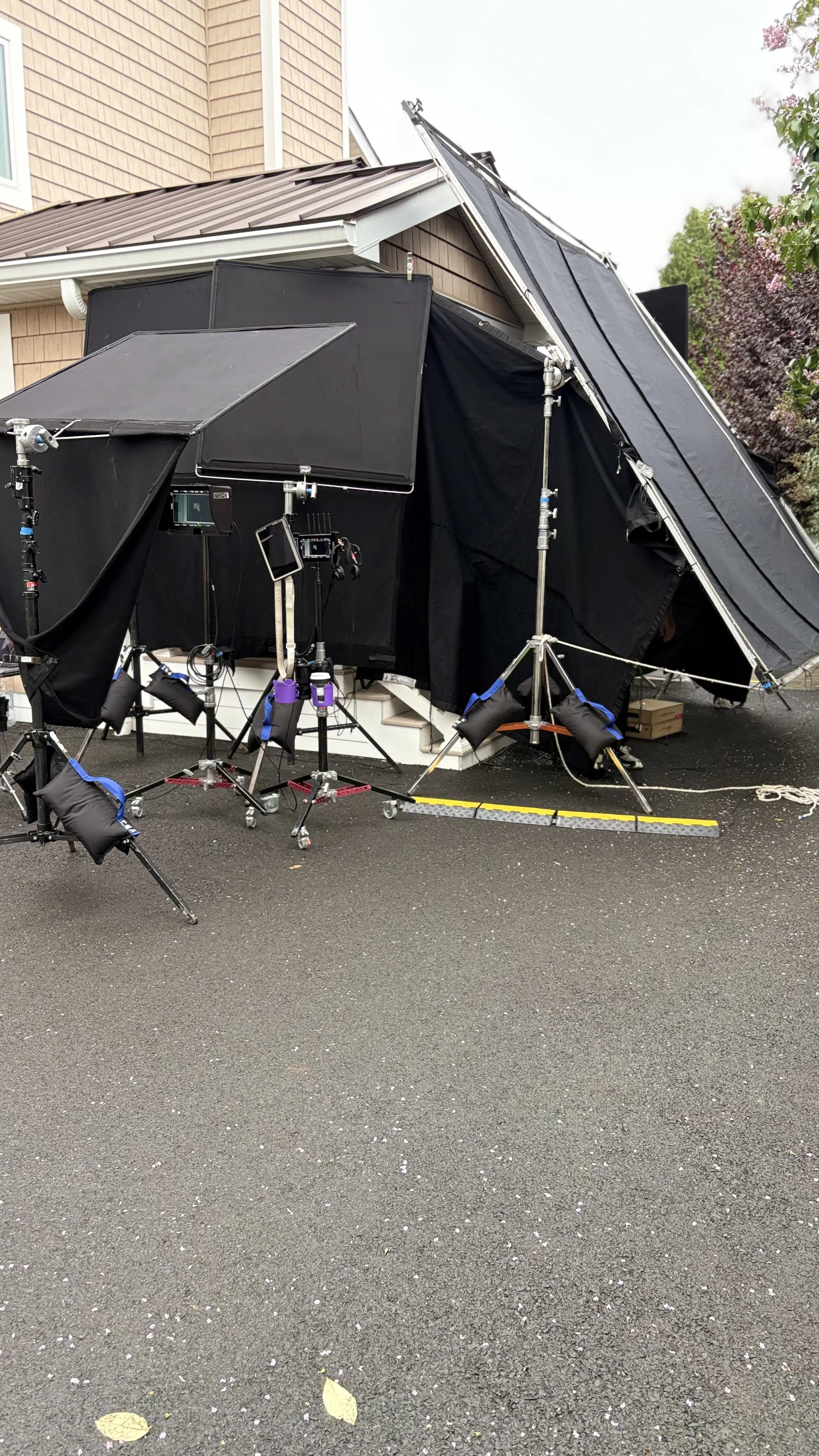Night for Day Grip and Light setups
Behind-the-scenes setup for filming or photography with lighting equipment, black fabric screens, and a house exterior in the background.