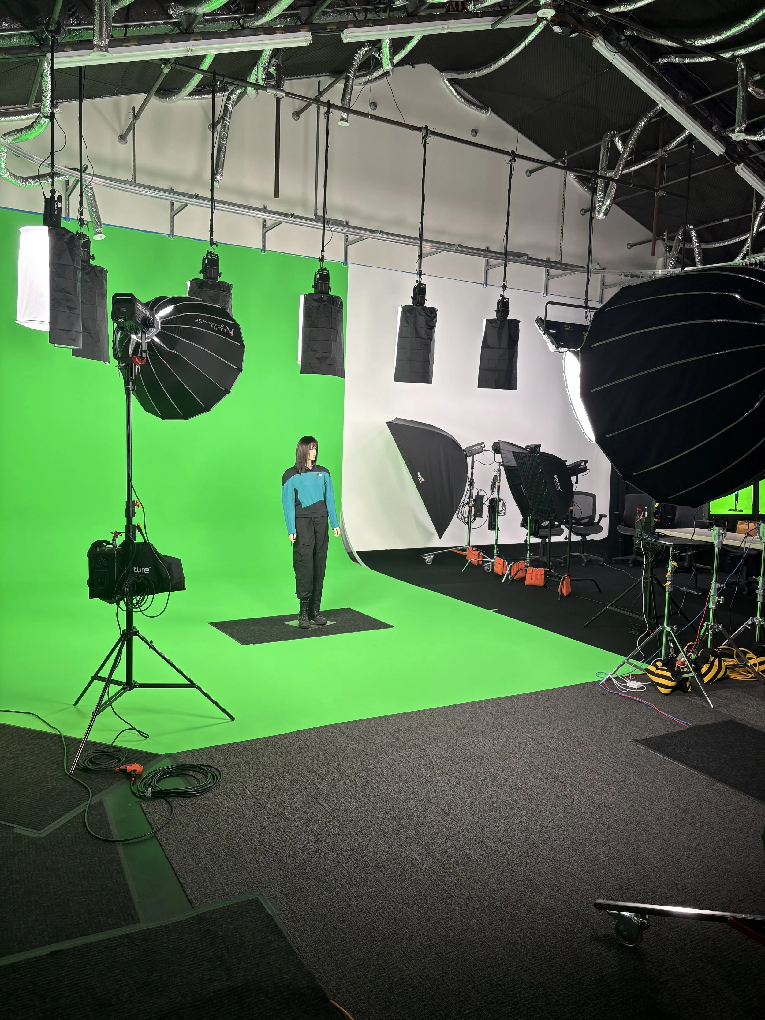 Historical Re-enactments: Grip work
Photo of a professional photography studio with a green chroma key backdrop, studio lighting equipment, including softboxes and umbrellas, and a person standing in front of the green screen. 