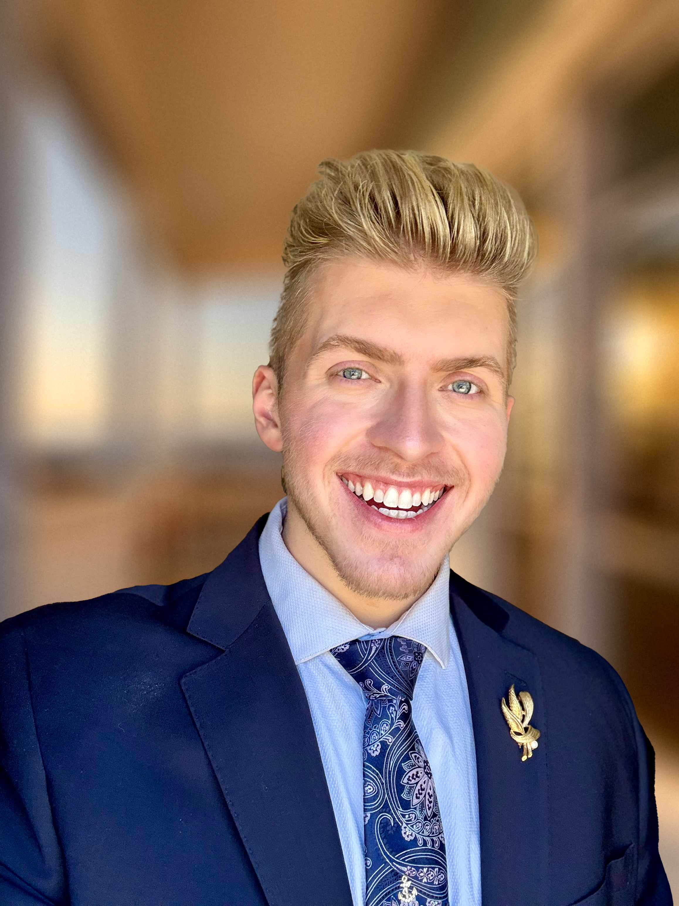 Person smiling at the camera with a sunset over water in the background, wearing a striped shirt.