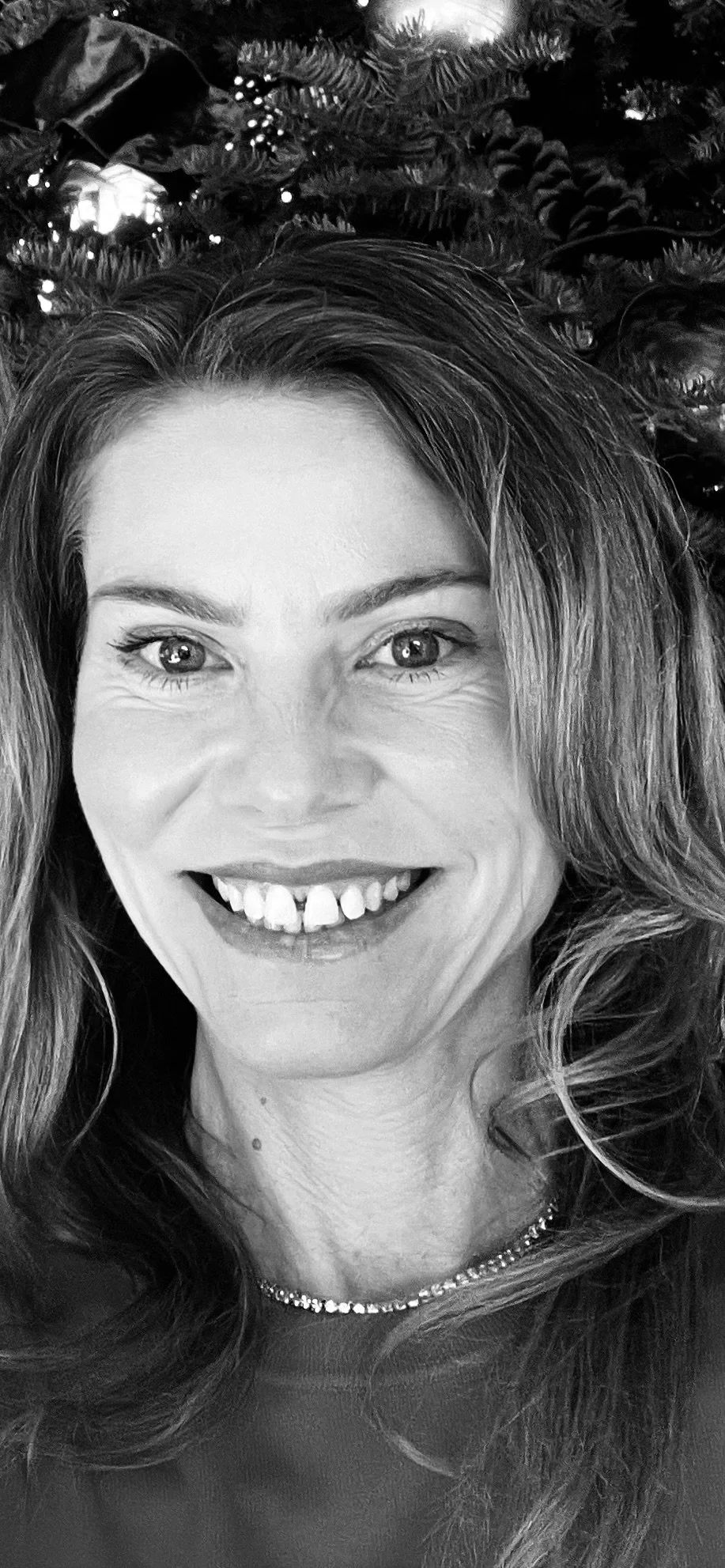 Dr. Rozlynn Myers smiling with wavy hair, wearing a beaded necklace, and radiant skin.