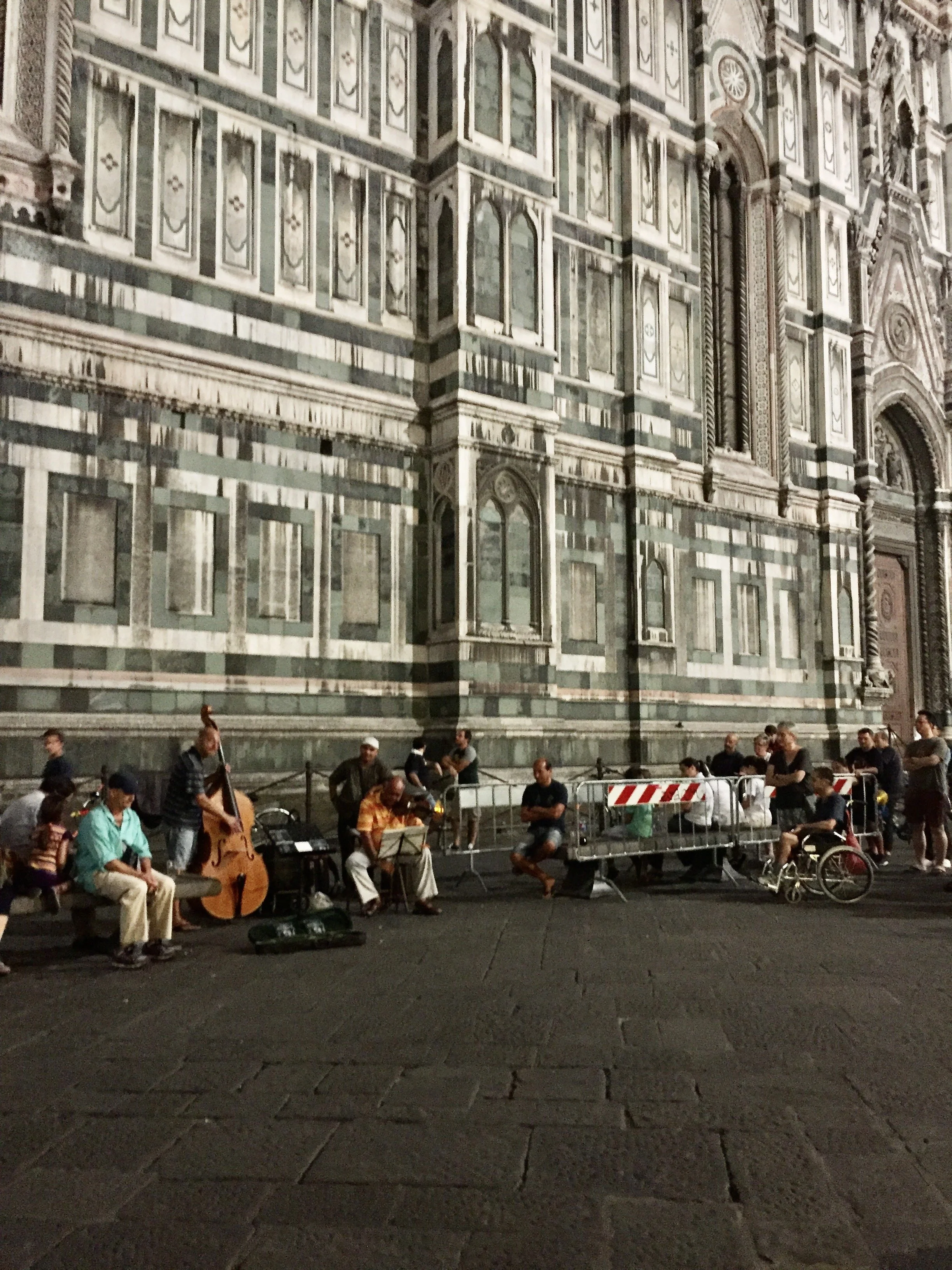 People sitting and playing music outside the Duomo in Florence, Italy.