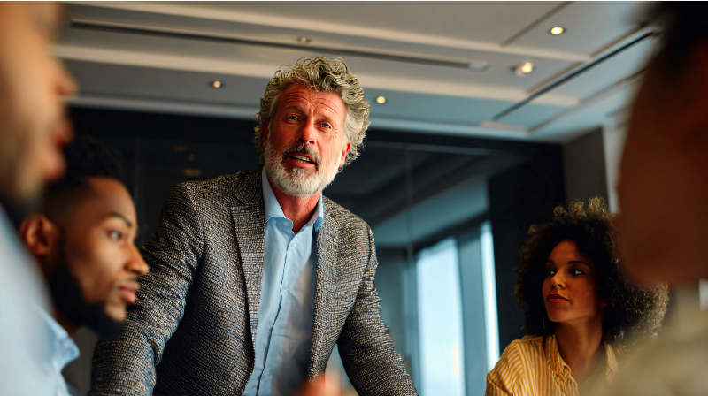 A senior professional speaking during a workplace discussion shaped by authority and accountability.