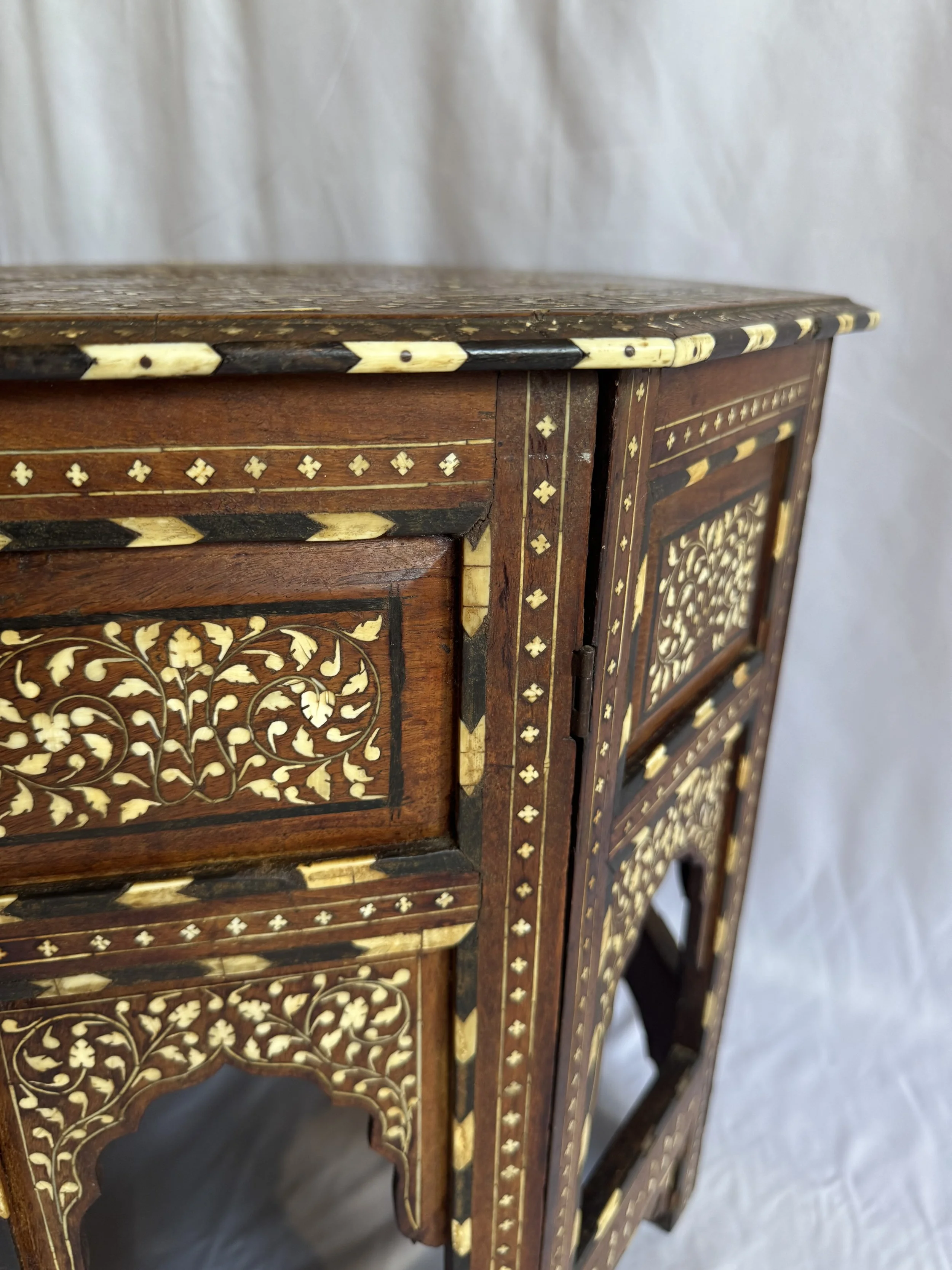 Close-up of an elegantly carved wooden furniture piece with intricate inlay work in floral and geometric patterns.