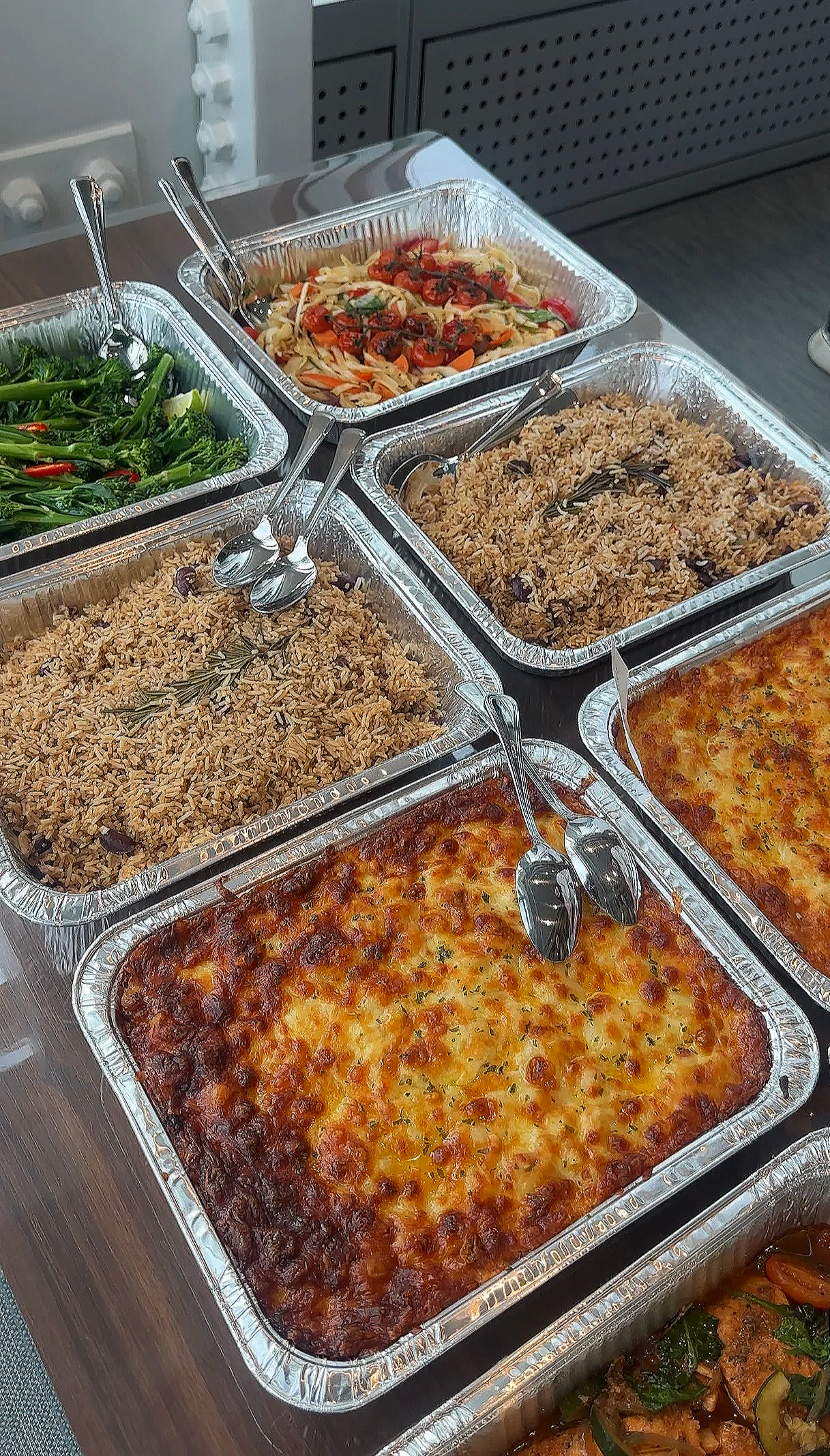 A buffet with trays of pasta, rice, lasagna, vegetables, and chicken dishes.