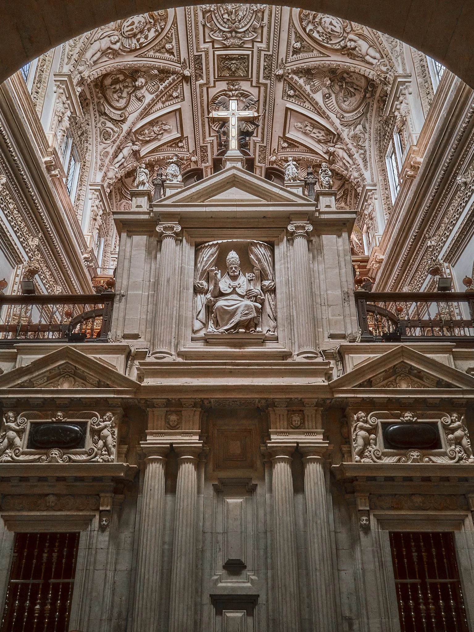 Interior de una iglesia con detalles arquitectónicos ornamentados y una estatua de un monarca en un altar