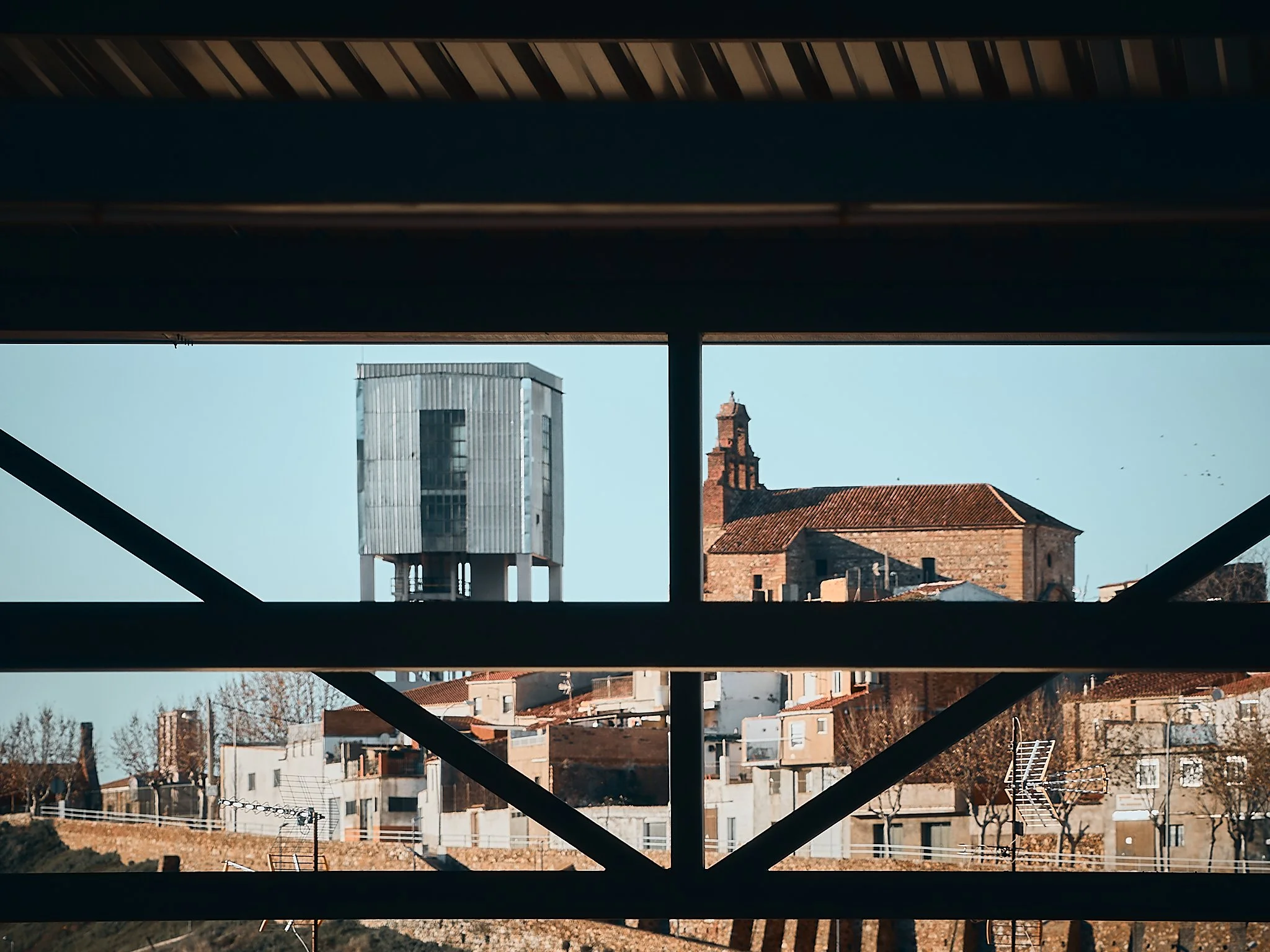 Vista de edificios, incluyendo uno de estructura moderna y un iglesia antigua, en un paisaje urbano.