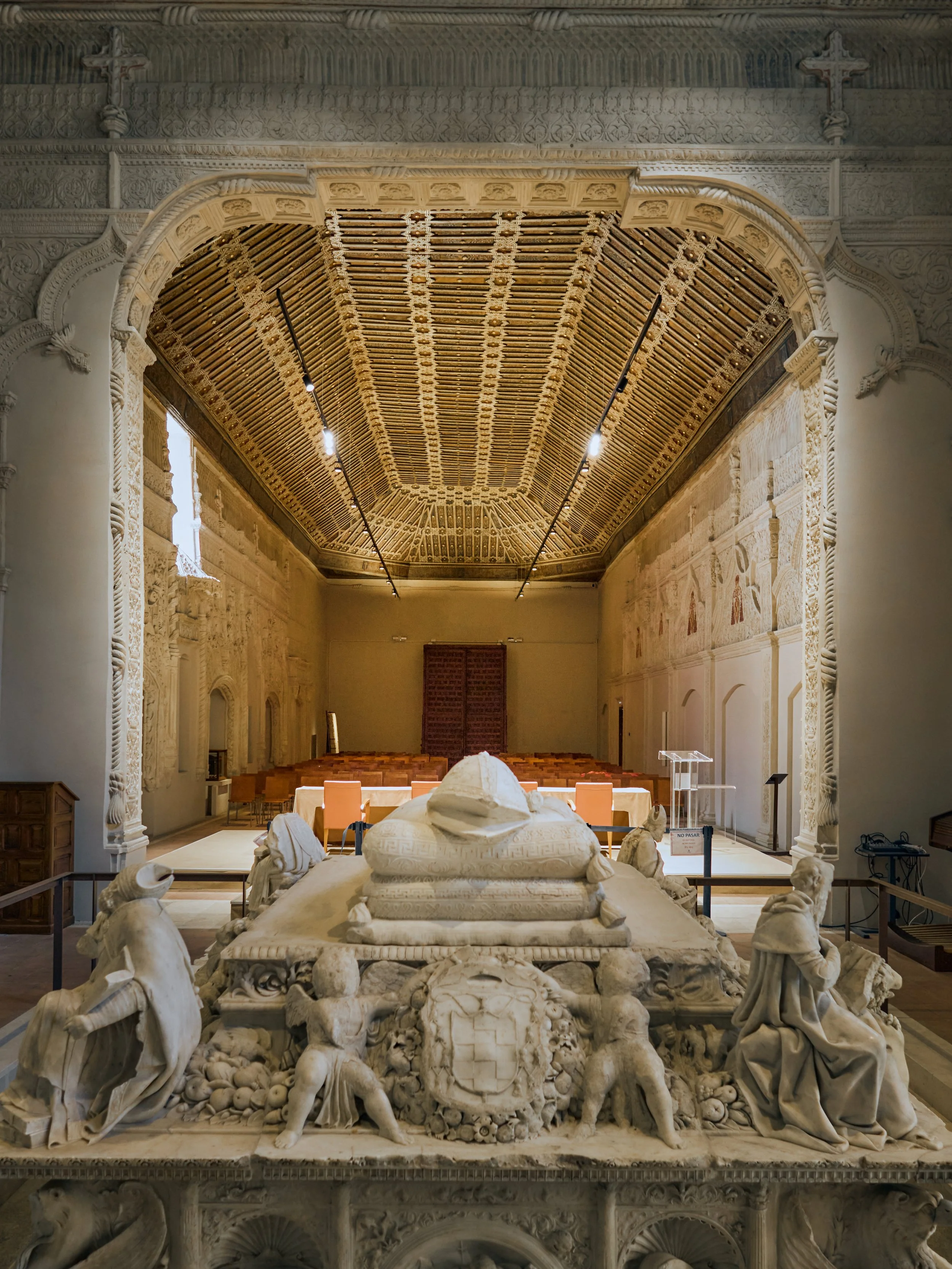 Capilla con altar decorado con esculturas de mármol, paredes con relieves y techo de madera tallada en una sala con arquitectura clásica.