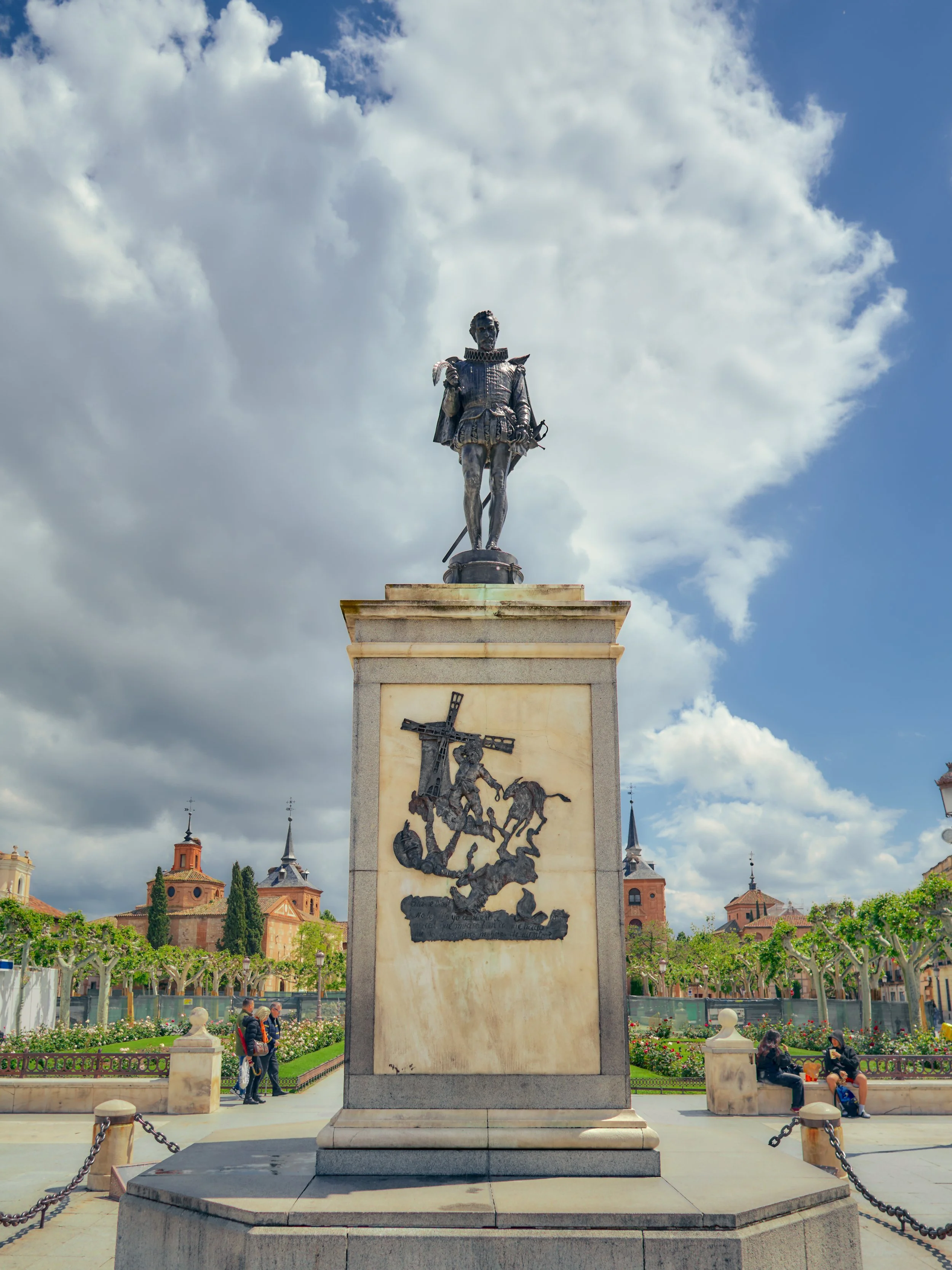 Escultura de un caballero en una plazuela con un fondo de edificios y un cielo nublado.
