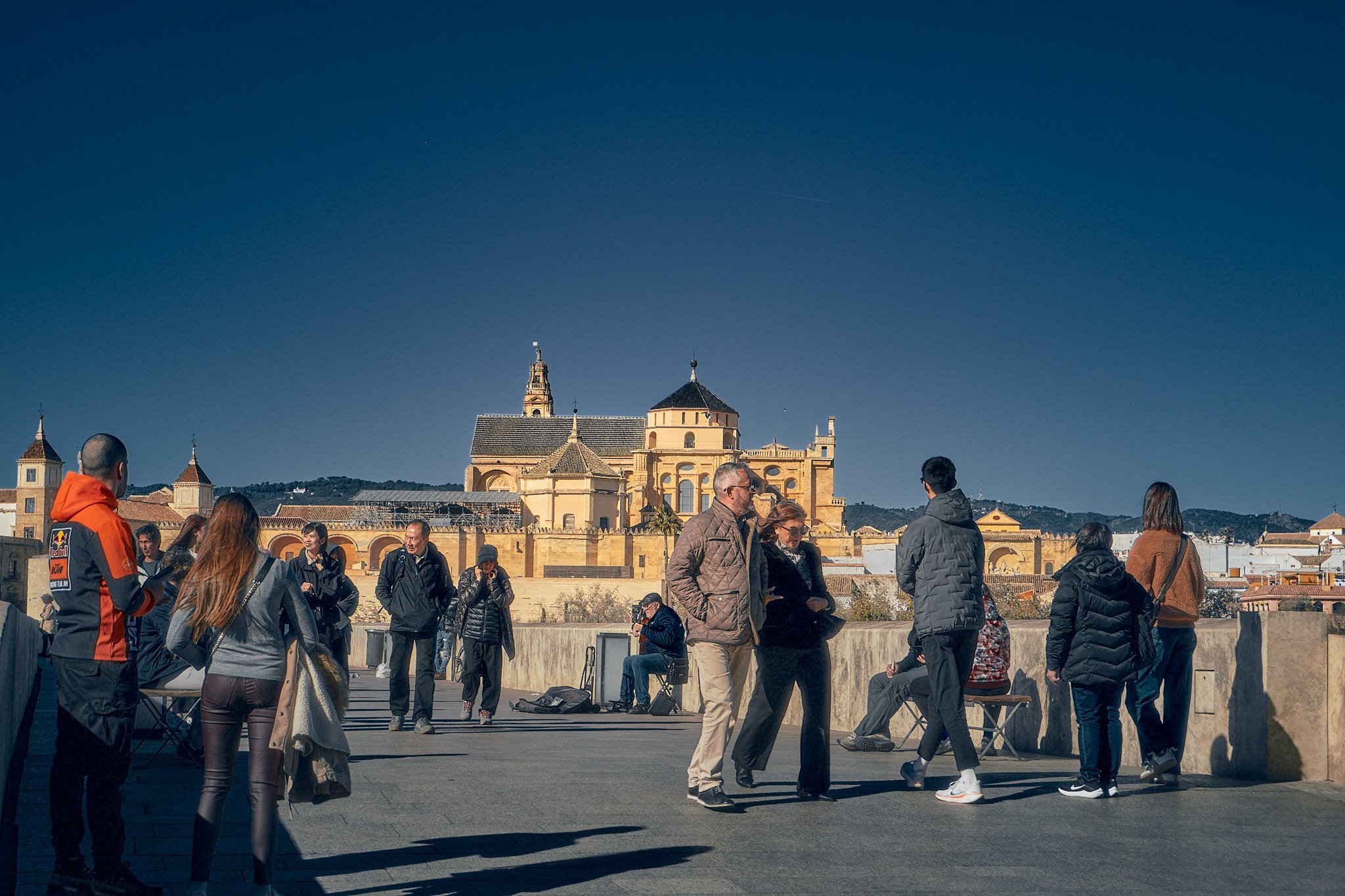 Grupo de personas en una terraza con vista a una catedral histórica en un día soleado.
