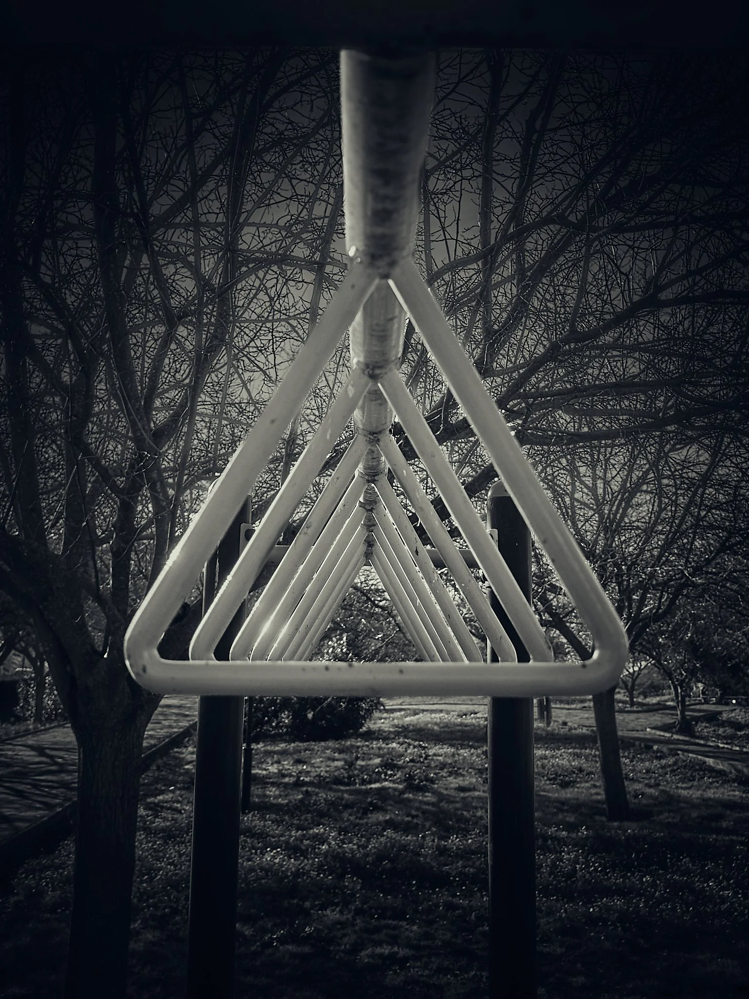 Estructura de resbaladilla metálica en un parque oscuro y sin niños.