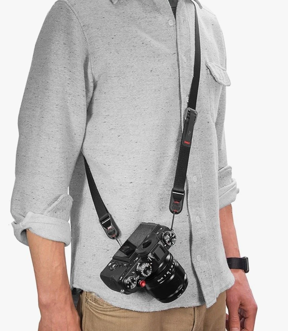 Persona con camisa gris llevar una cámara réflex con correa negra