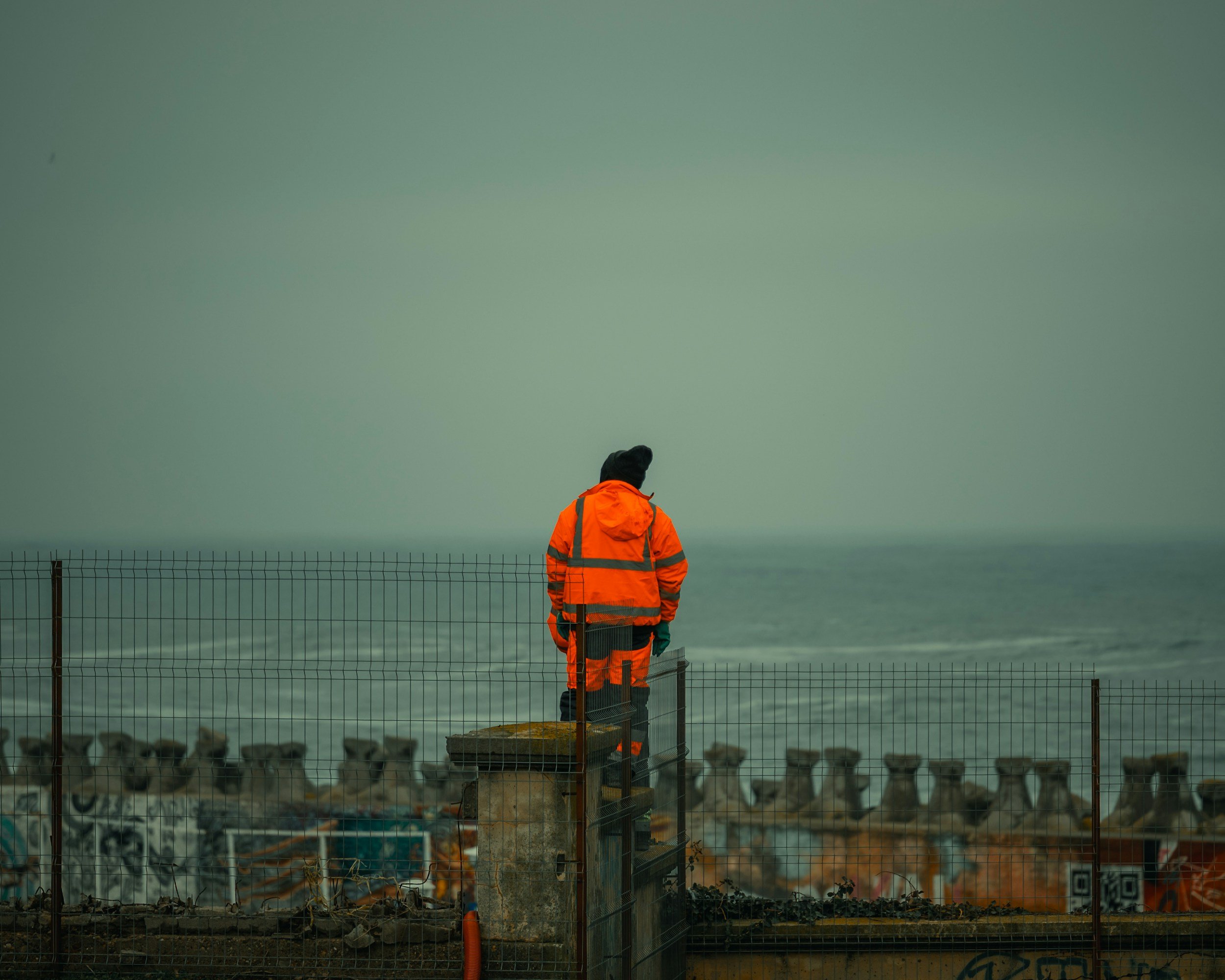 Worker in high-visibility workwear looking out to sea