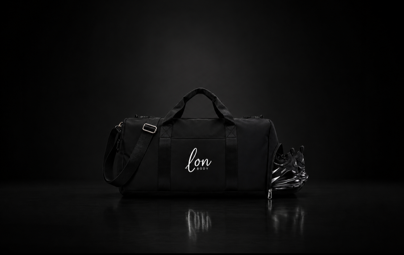 A black duffel bag with the words "LON BODY" in whiteed text, sitting on a reflective surface with a dark background, with a pair of black sneakers partially visible beside it.