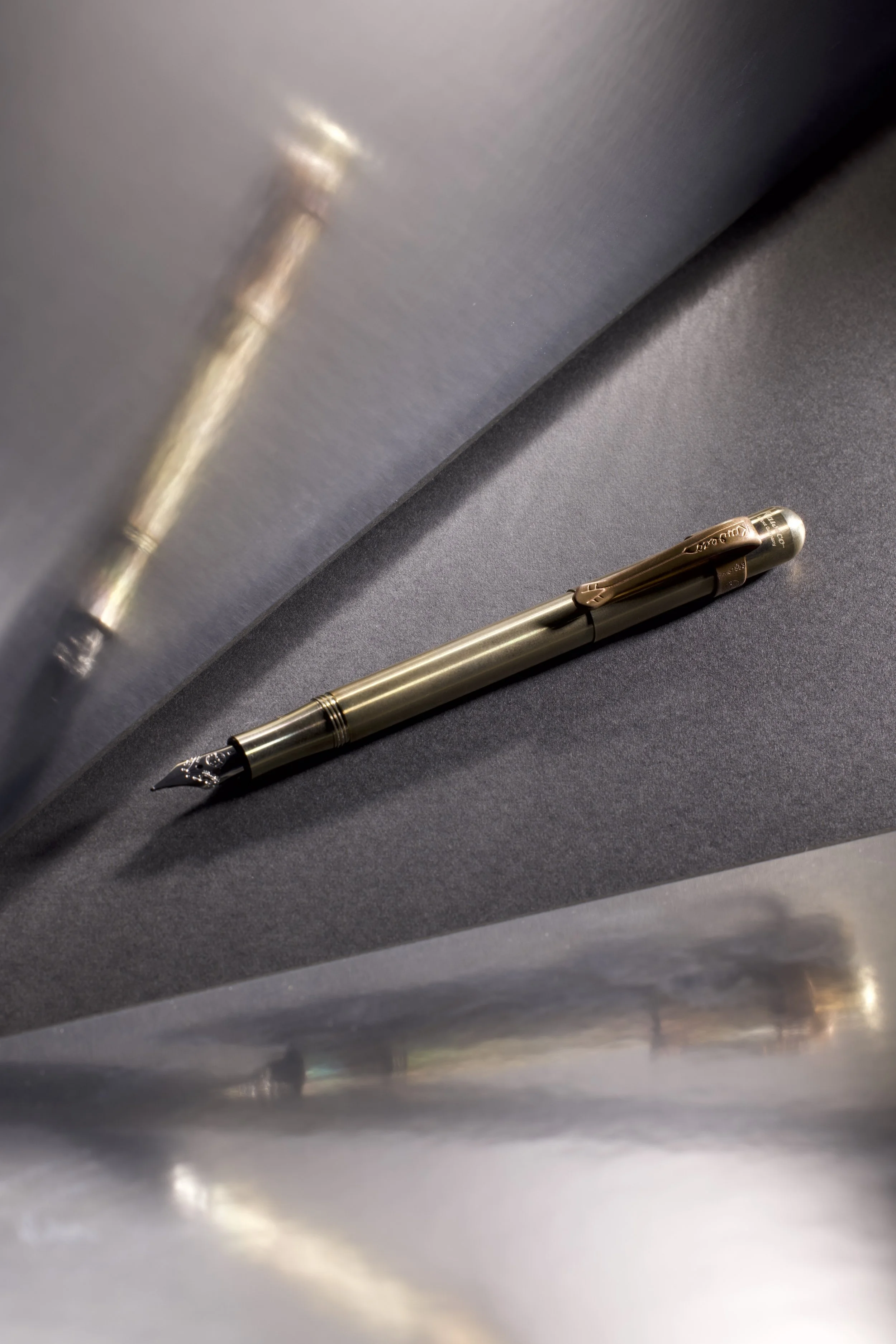 Black and gold fountain pen photographed with dramatic lighting and reflections