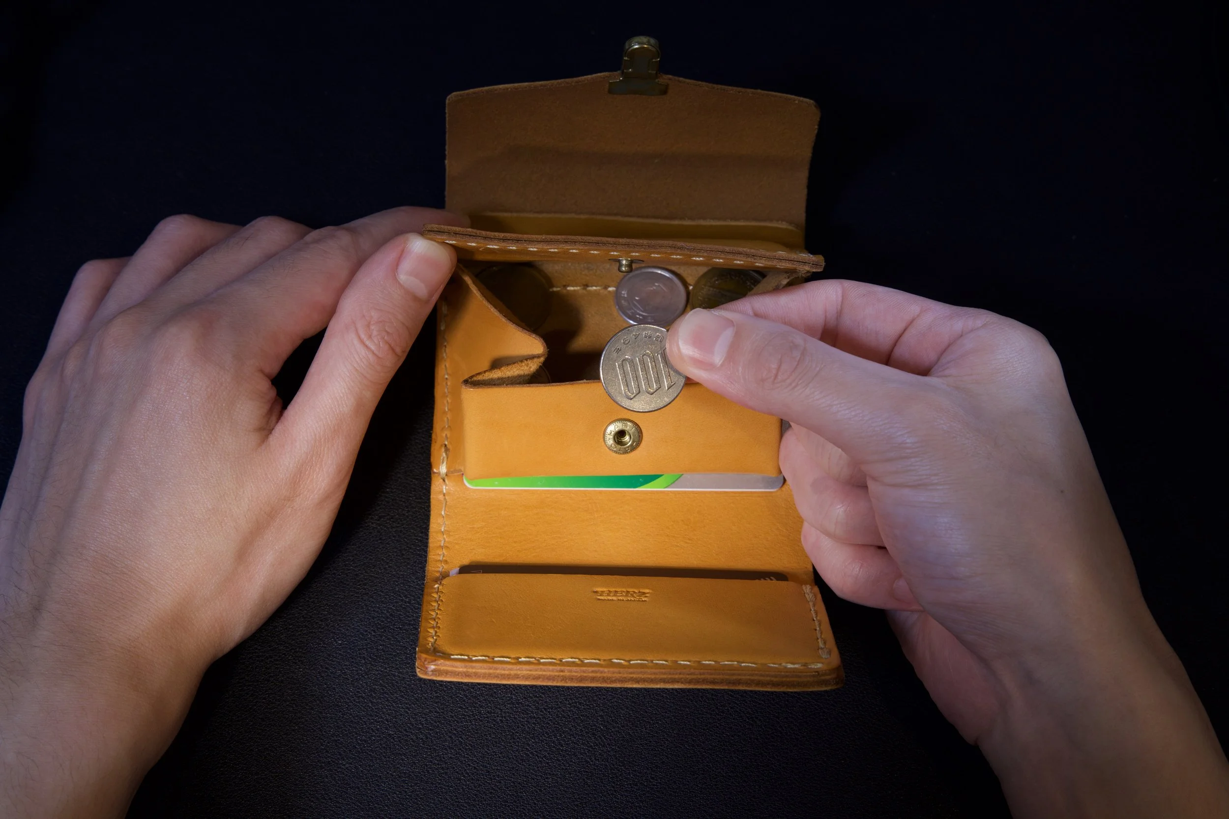 Textured leather wallet photographed with dramatic light and shadow.