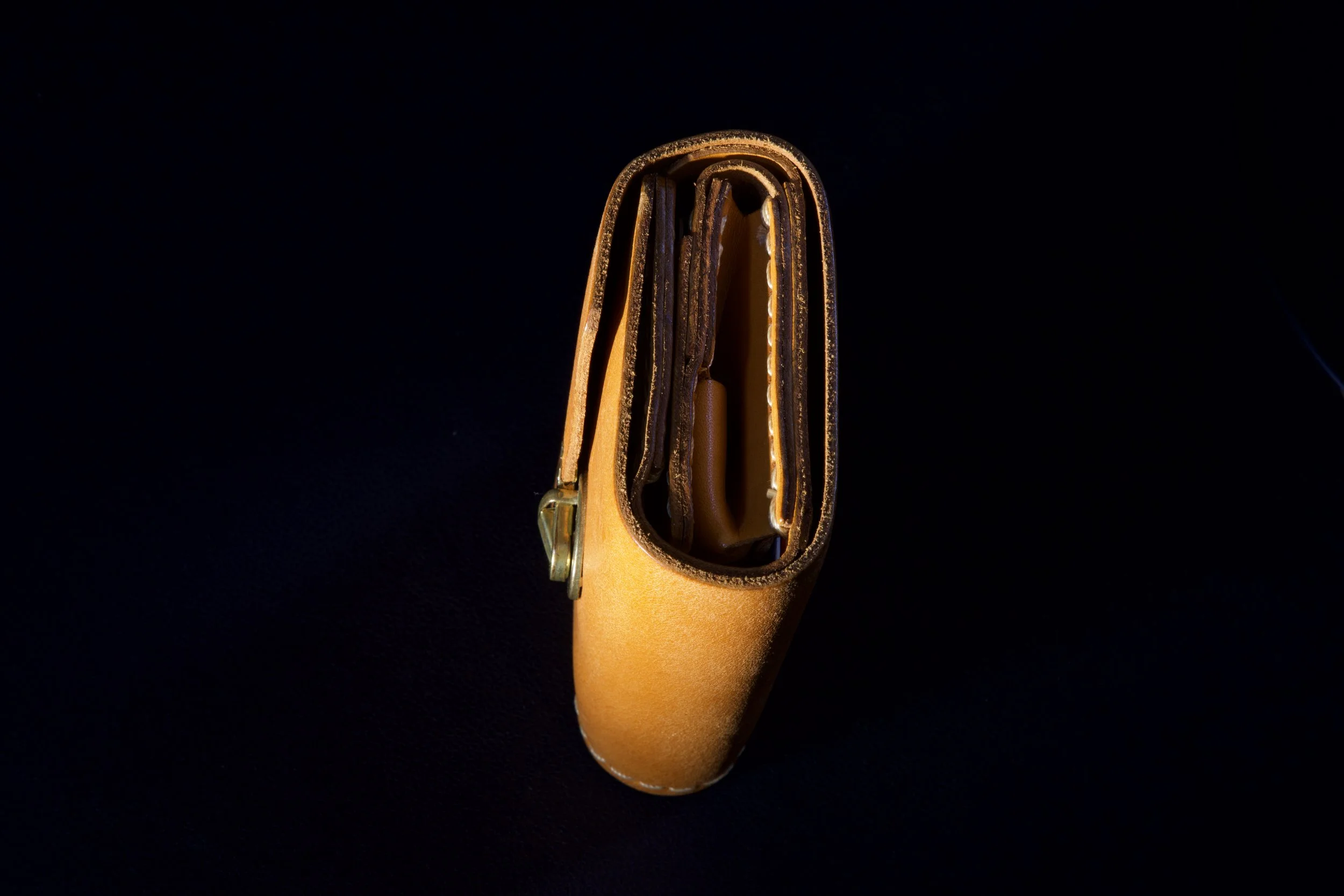 Top-down view of a partially open brown leather wallet on a black background.