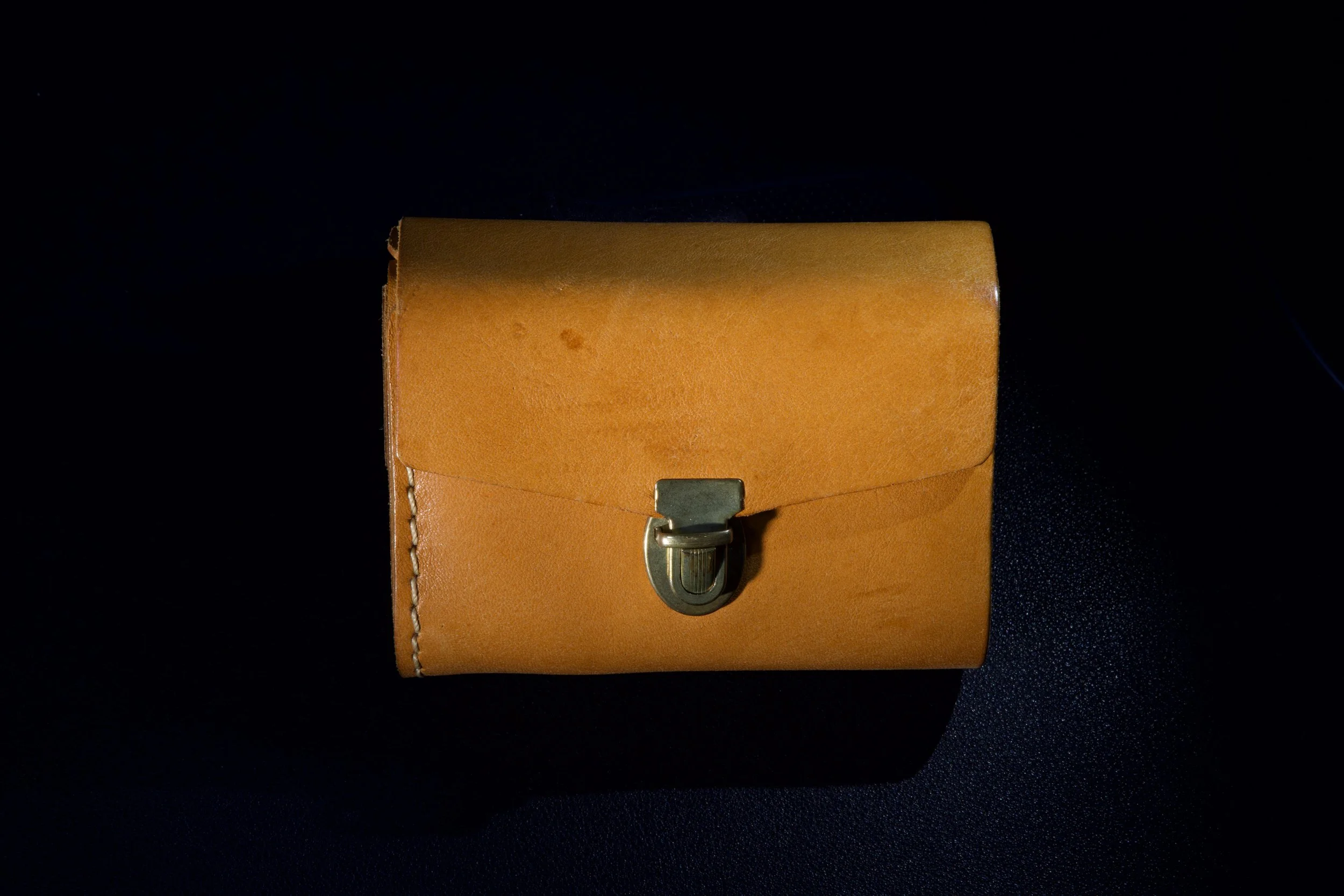 Textured leather wallet photographed with dramatic light and shadow.