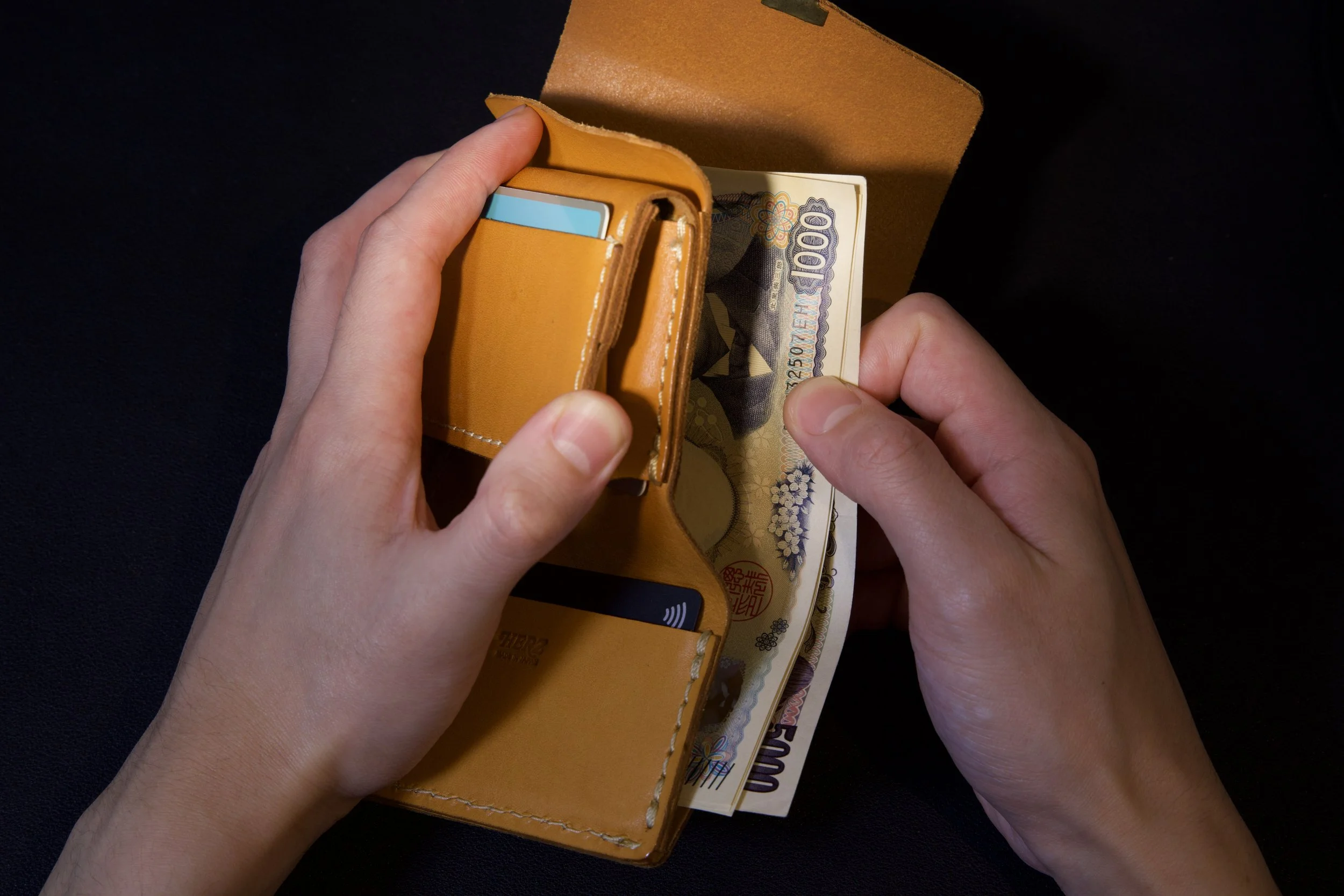 Textured leather wallet photographed with dramatic light and shadow.