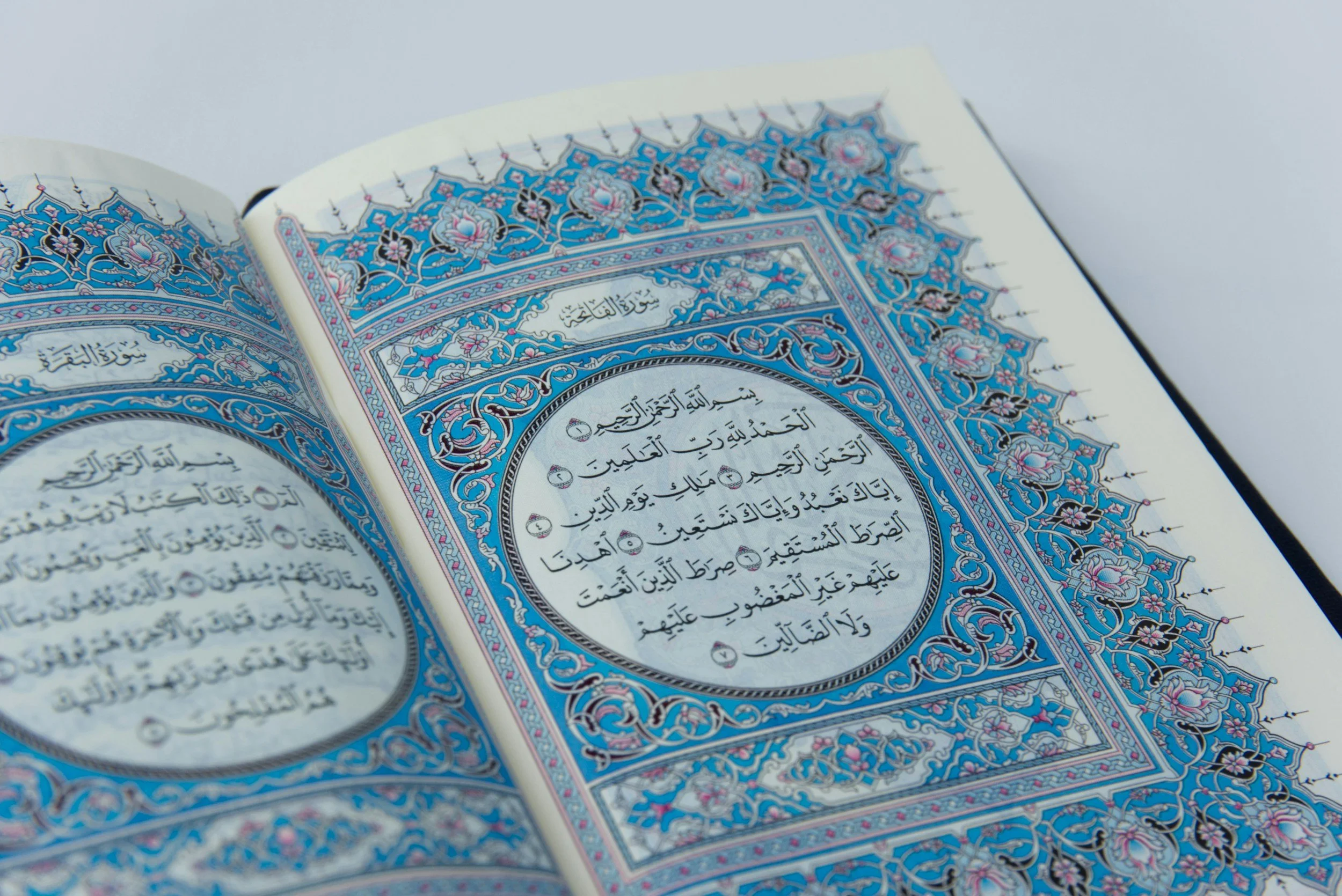 Open pages of the Quran with ornamental Arabic calligraphy and decorative borders.