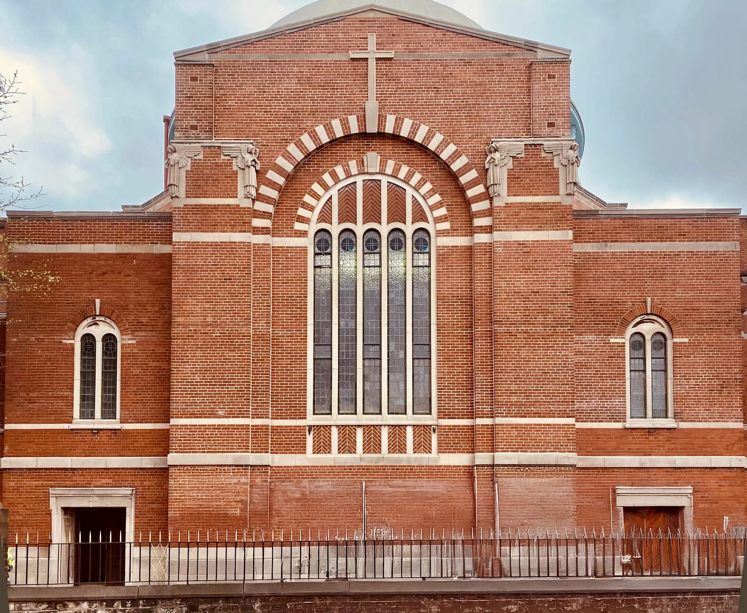 St John The Baptist, Rochdale, with tall arched windows, decorative stonework, and a cross on the roof.