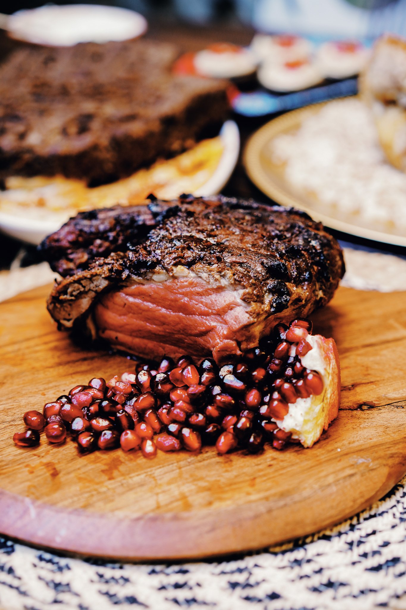 Sliced open beef tenderloin with pomegranate seeds on wooden board