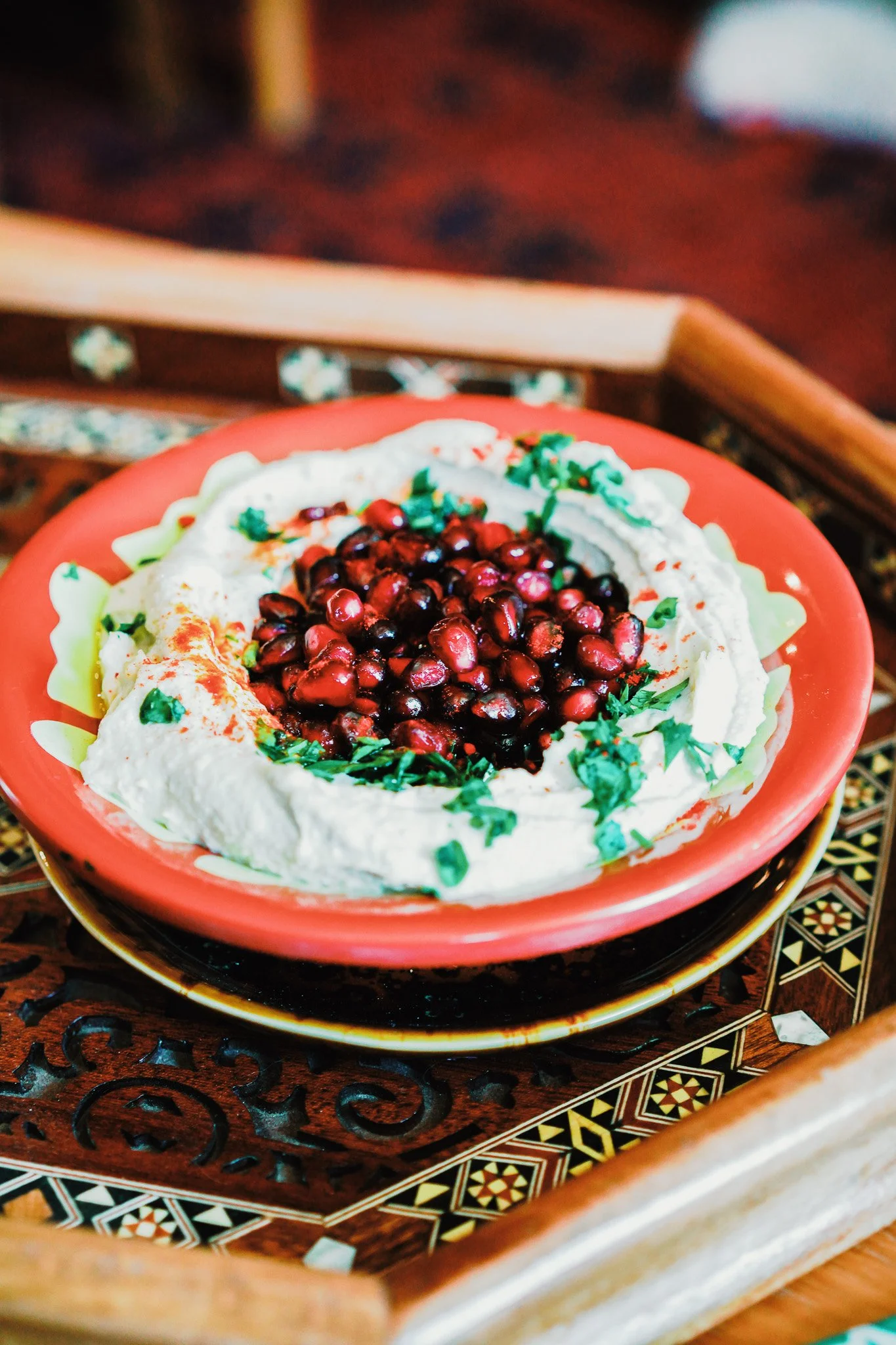 Bowl of hummus in traditional bowl on wooden tray