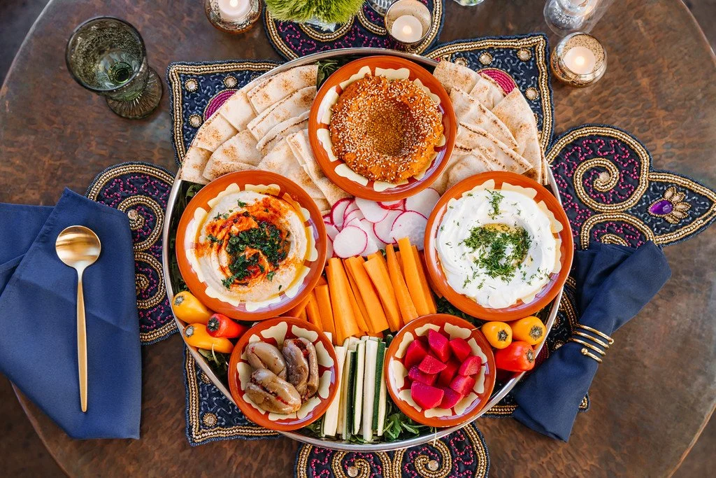 Bright platter of mezze dips and pickles on silver platter with blue and beaded accents
