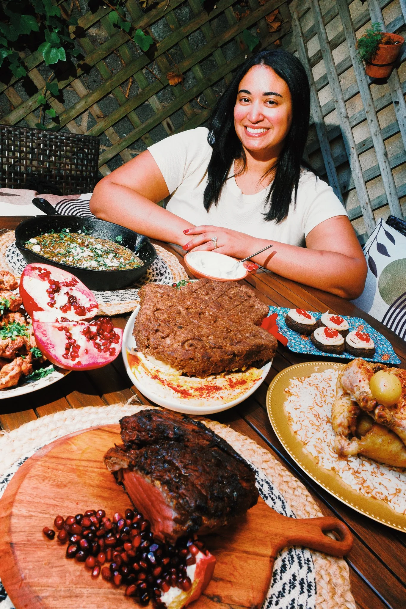 Chef Miranda sitting and smiling over table full of her food