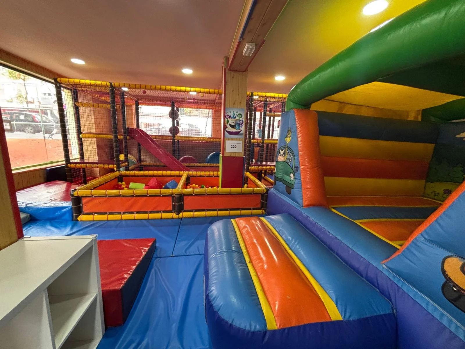 Zona de juegos infantiles con diferentes estructuras inflables de colores, incluyendo resbaladillas y áreas acolchonadas.