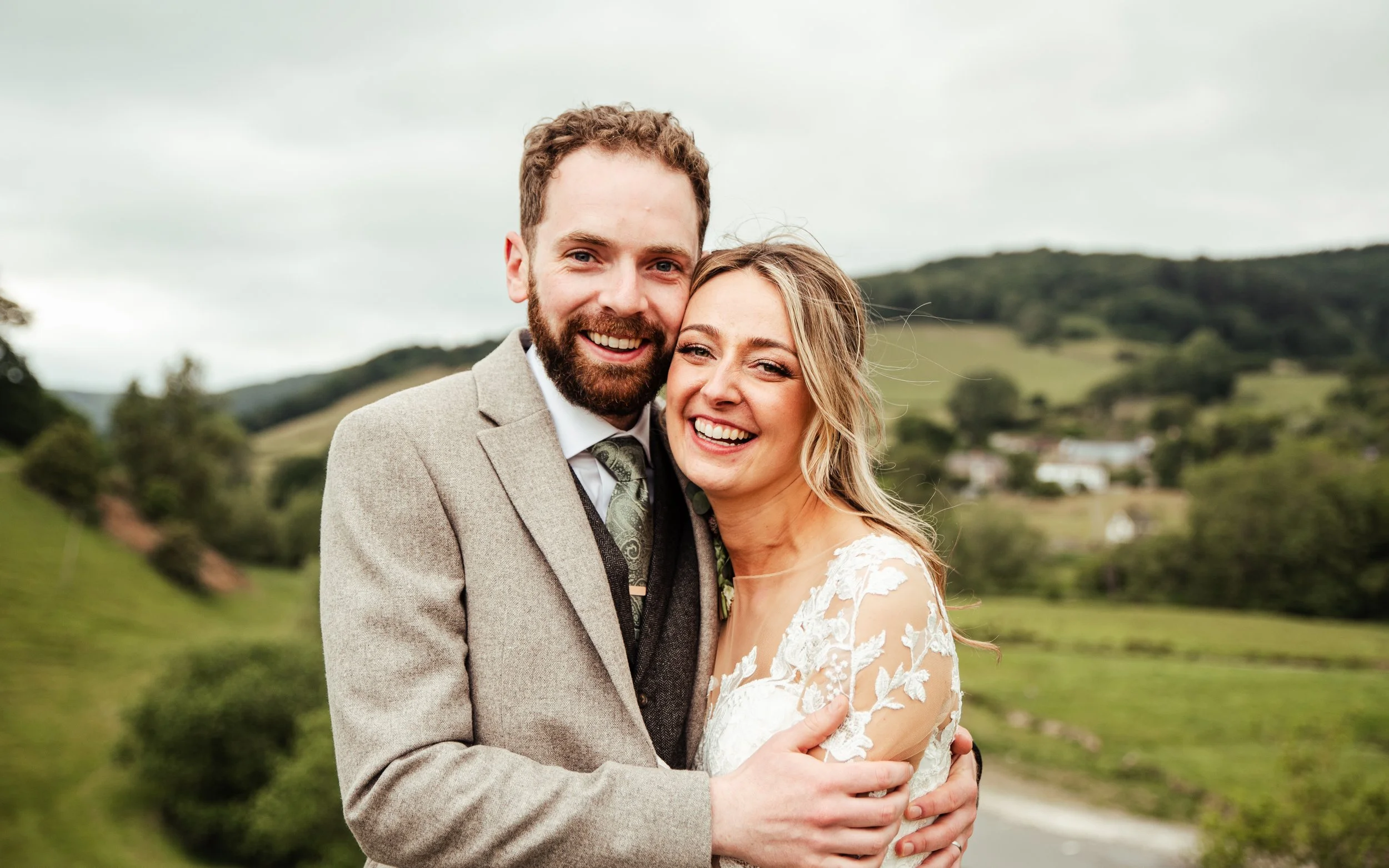 A smiling couple embracing outdoors on their wedding day, by Jess from Jessica Laura Weddings. Wedding Planner & Coordinator. Based in Shropshire. Bringing your vision to life with seamless, unforgettable weddings.