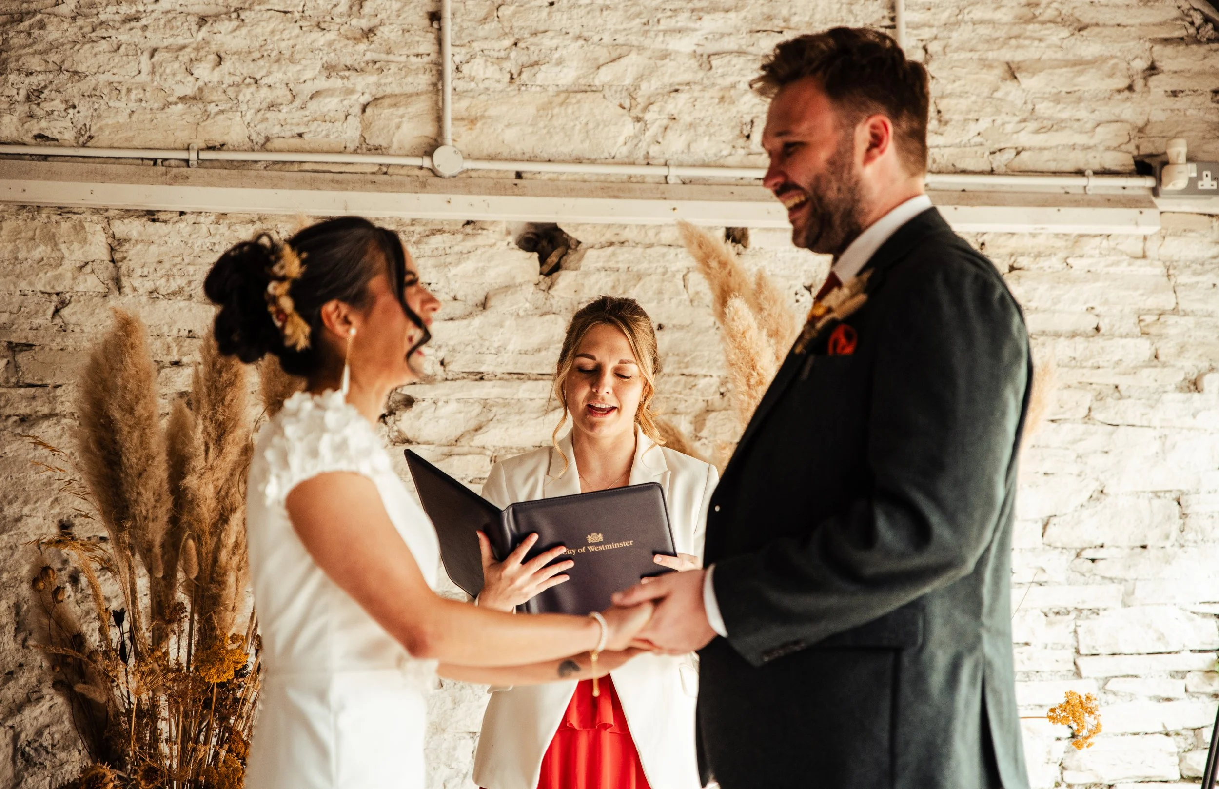 A bride and groom holding hands during their barn wedding ceremony, by Jess from Jessica Laura Weddings. Wedding Planner & Coordinator. Based in Shropshire. Bringing your vision to life with seamless, unforgettable weddings.