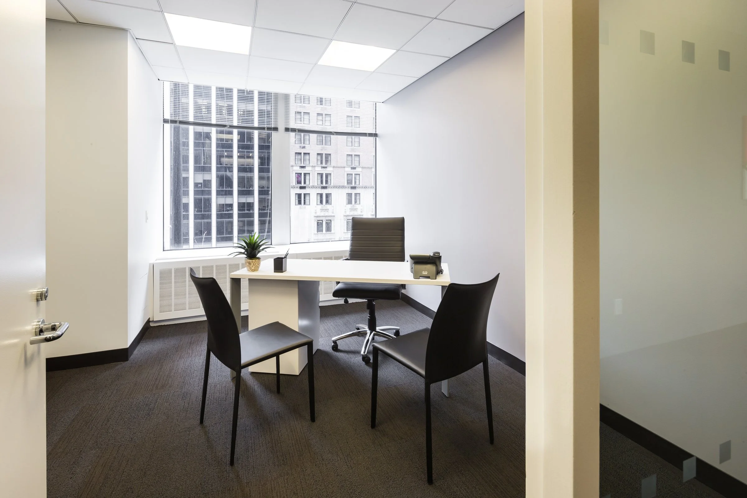 Window Furnished private office space for rent in Midtown Manhattan with a desk, guest chairs, and city views