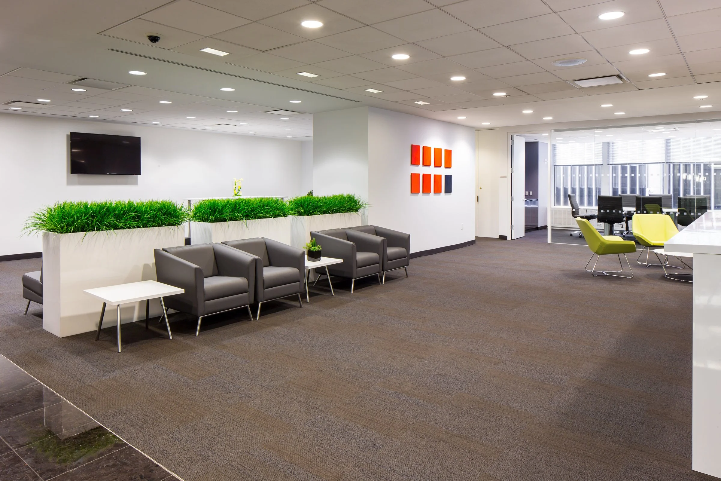 Office space client waiting area in Midtown Manhattan with armchair seating and a windowed conference room