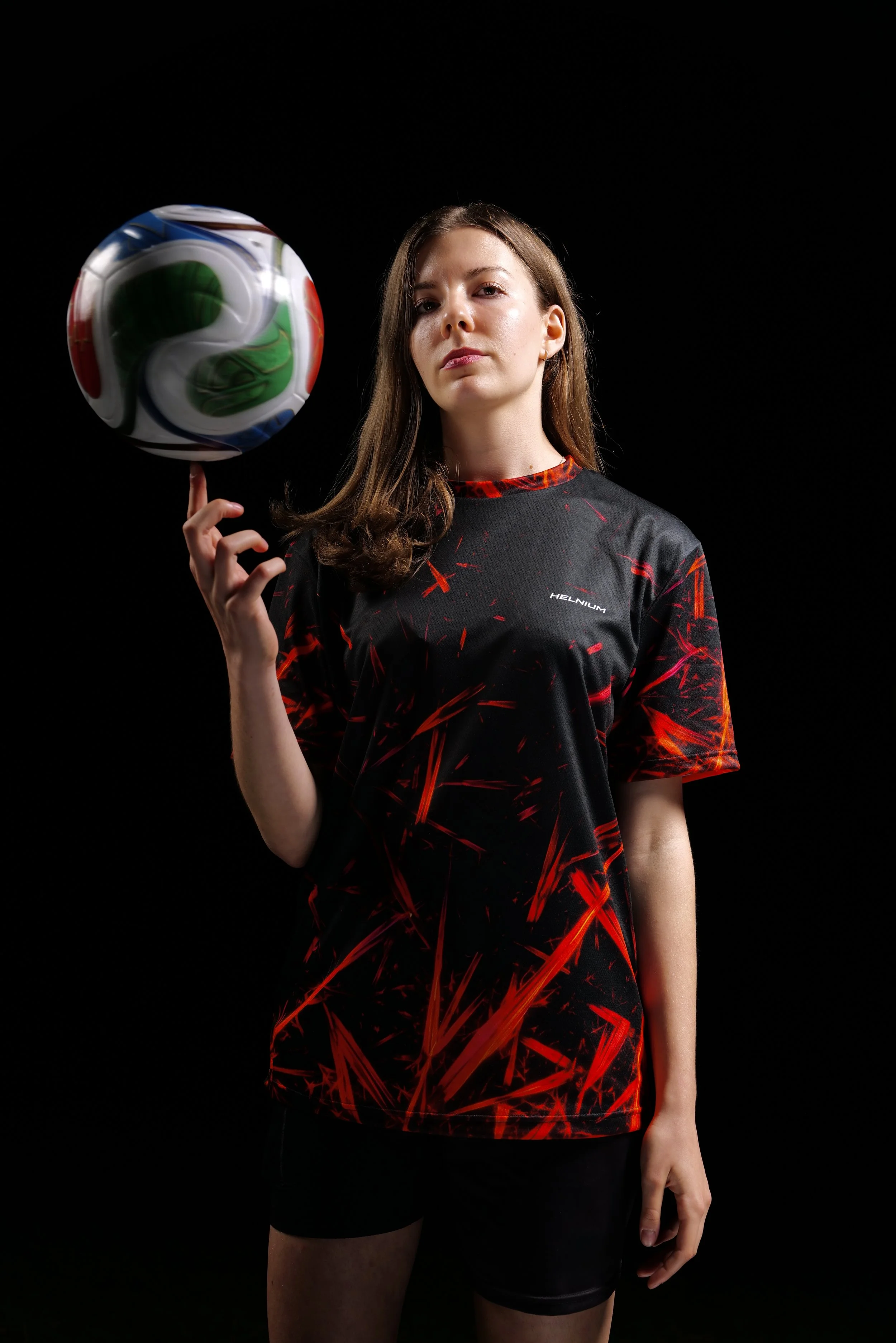Vitamin B12 crystal football jersey by Helnium, black sportswear featuring authentic red cyanocobalamin crystal microscopy, photographed on a model holding a football