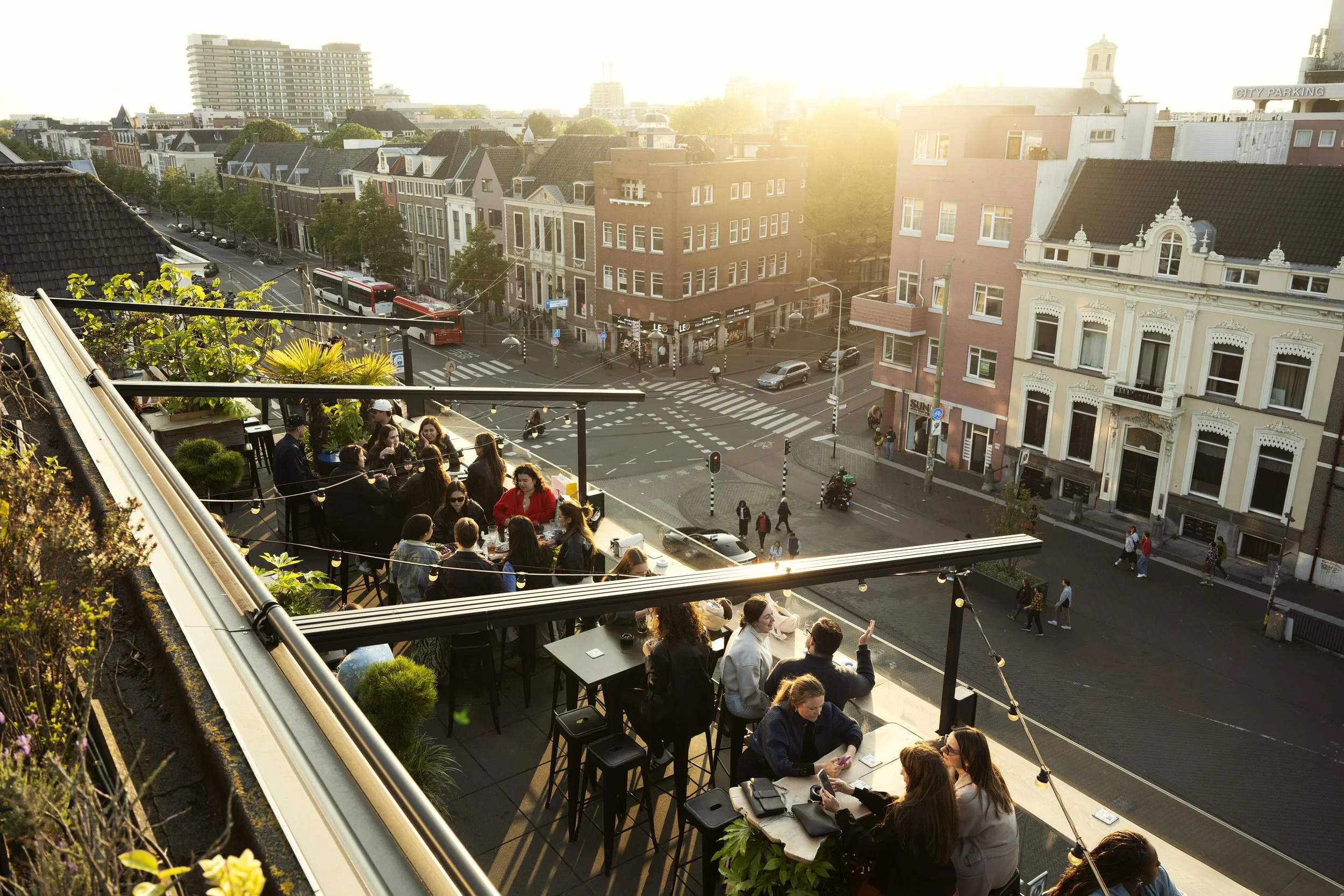 gasten die een drankje drinken op een rooftop bar in den haag met uitzicht over het stadscentrum