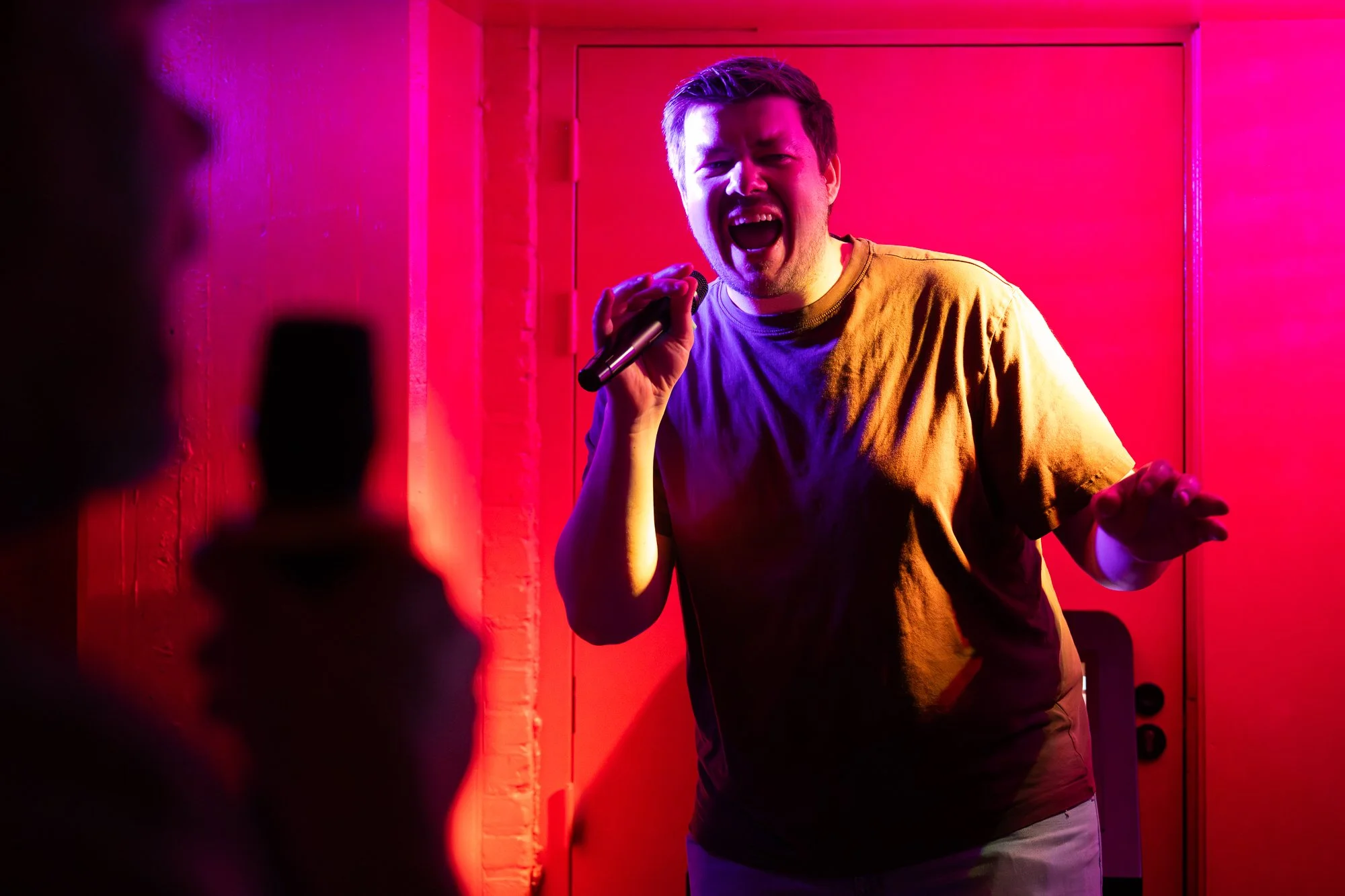 Een man die erg geniet van het zingen van zijn favoriete karaoke-nummers bij BLÊR private booth karaoke in het centrum van Den Haag